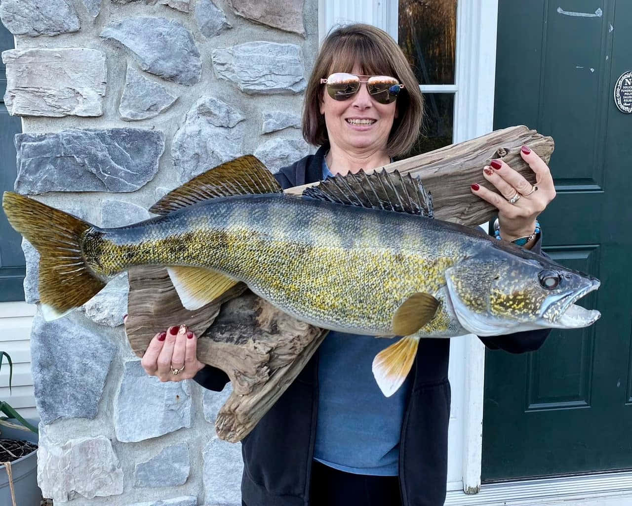 A Woman Holding A Large Fish In Front Of A House