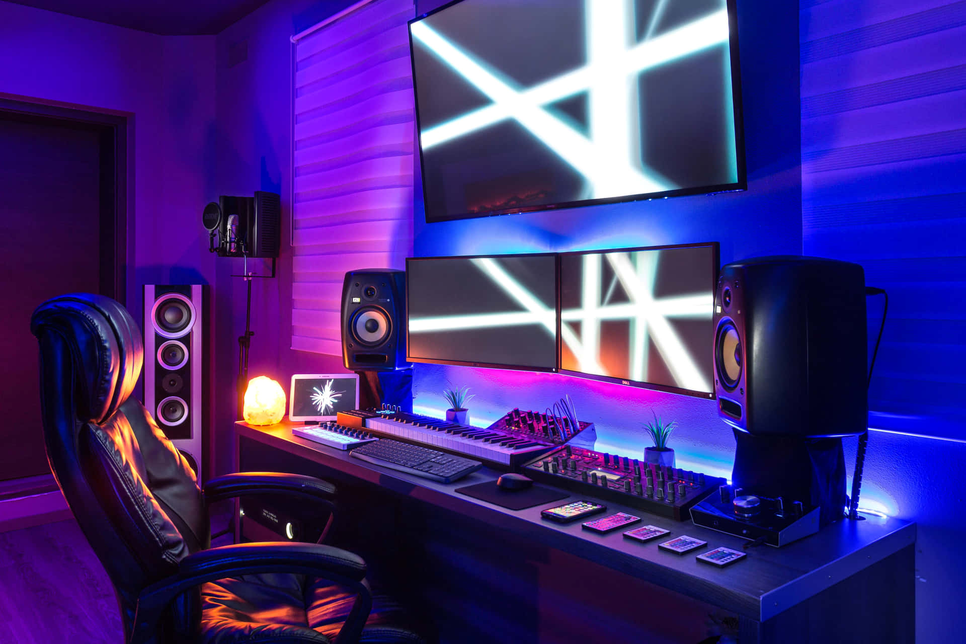 Ultimate Gaming PC Setup Wallpaper — A sleek gaming setup bathed in vibrant purple and blue neon light with multiple monitors and high-end audio equipment.