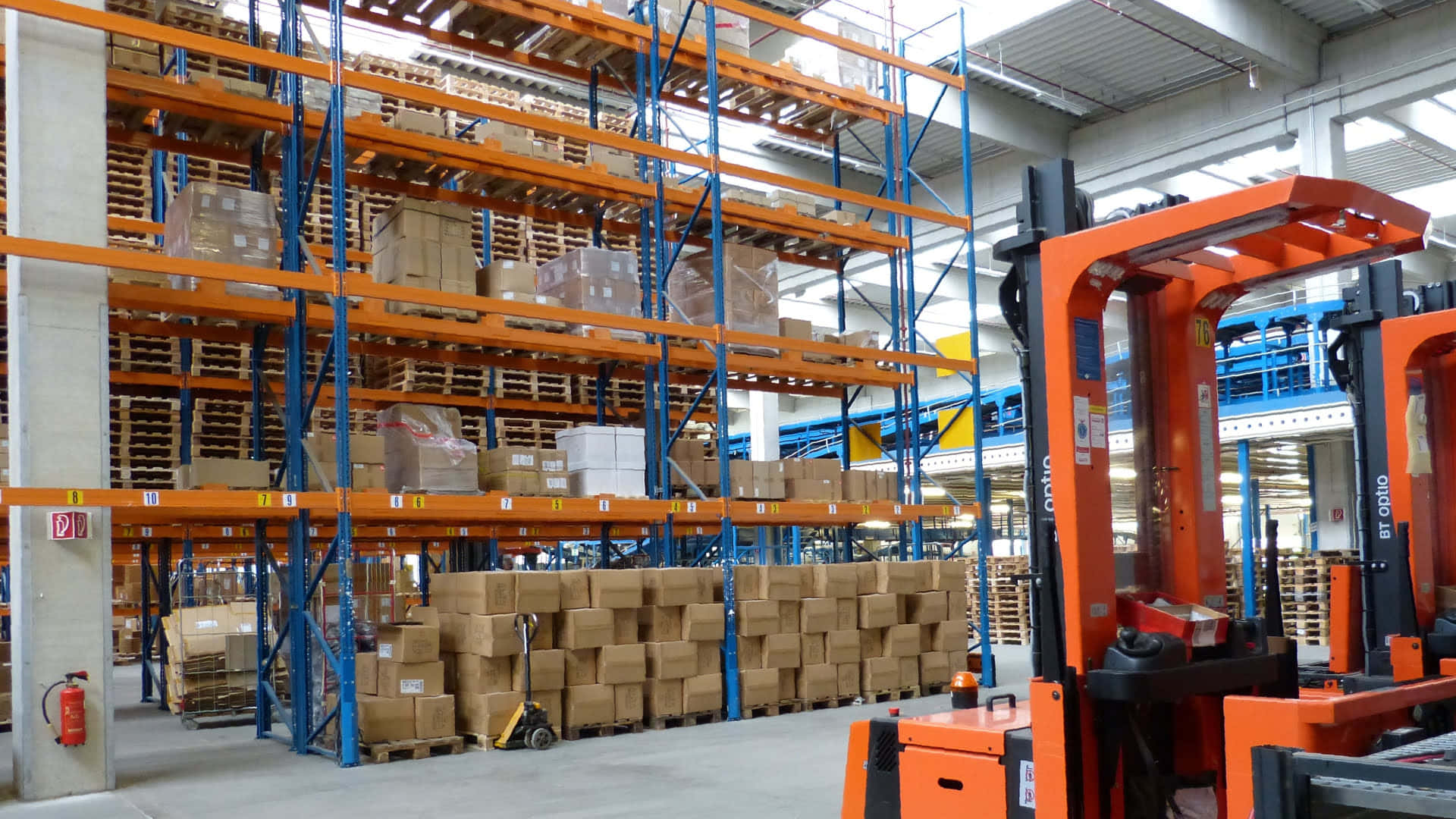A Warehouse With Orange Forklifts And Boxes