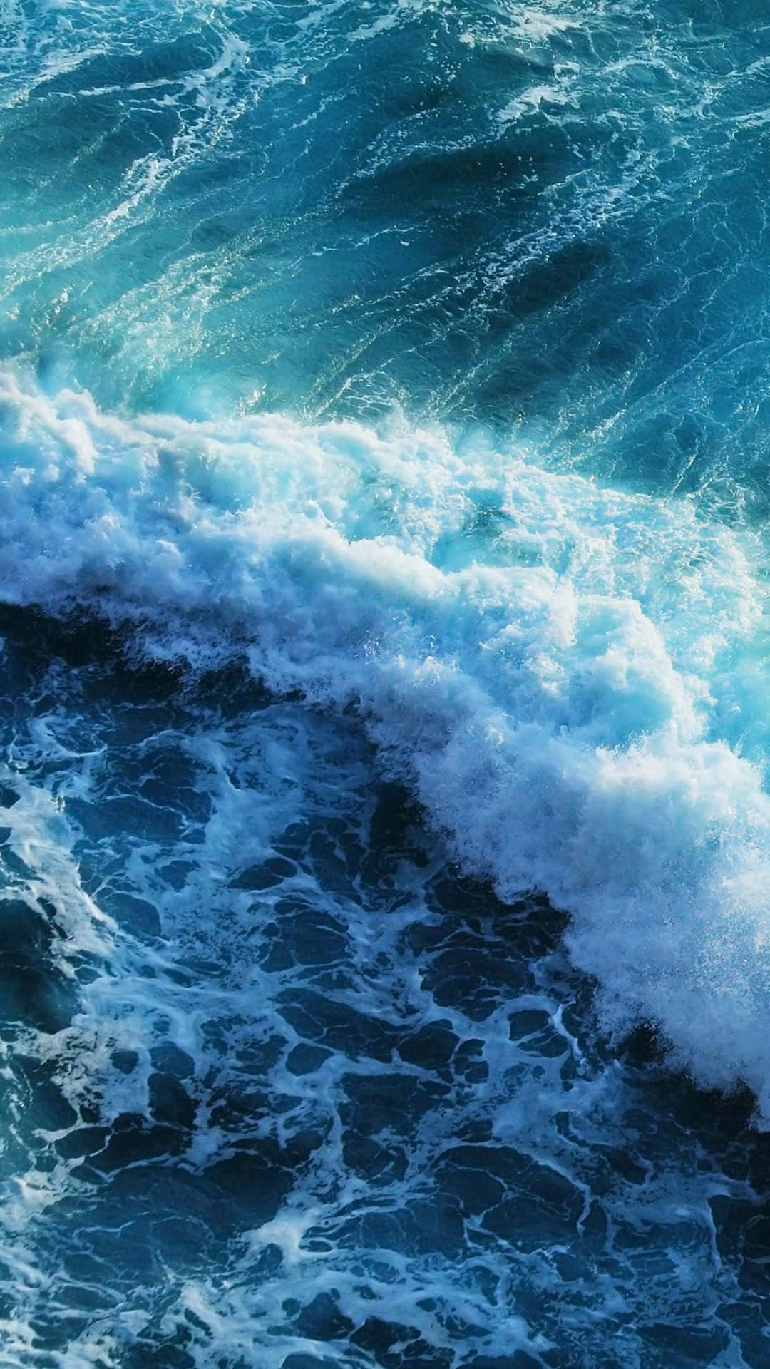 A Blue Ocean With Waves Crashing Over It Wallpaper