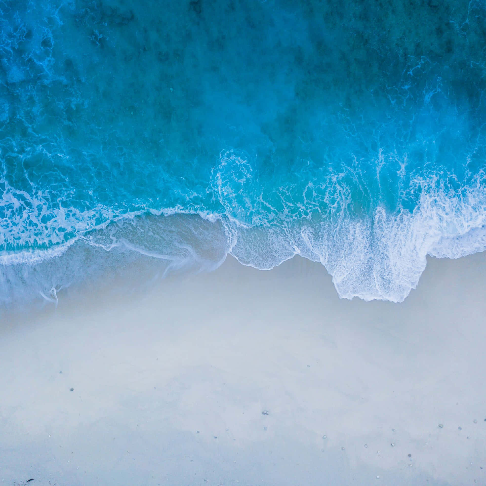 A Blue Wave Is Crashing On The Beach Wallpaper