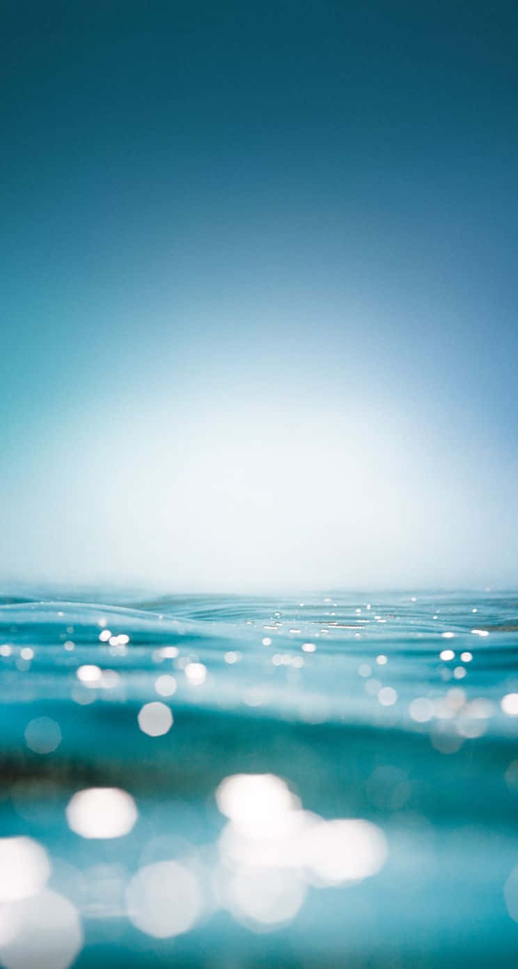 Wallpaperupplev En Surrealistisk Vy Över Det Blå Havet Genom Vatten-iphone-bakgrundsbilden. Wallpaper