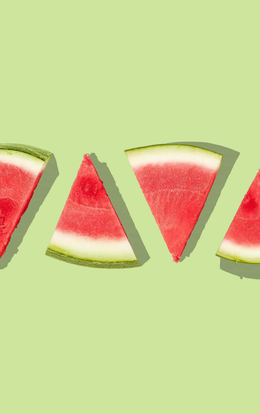 Watermelon Slices In Triangles On A Green Background Wallpaper