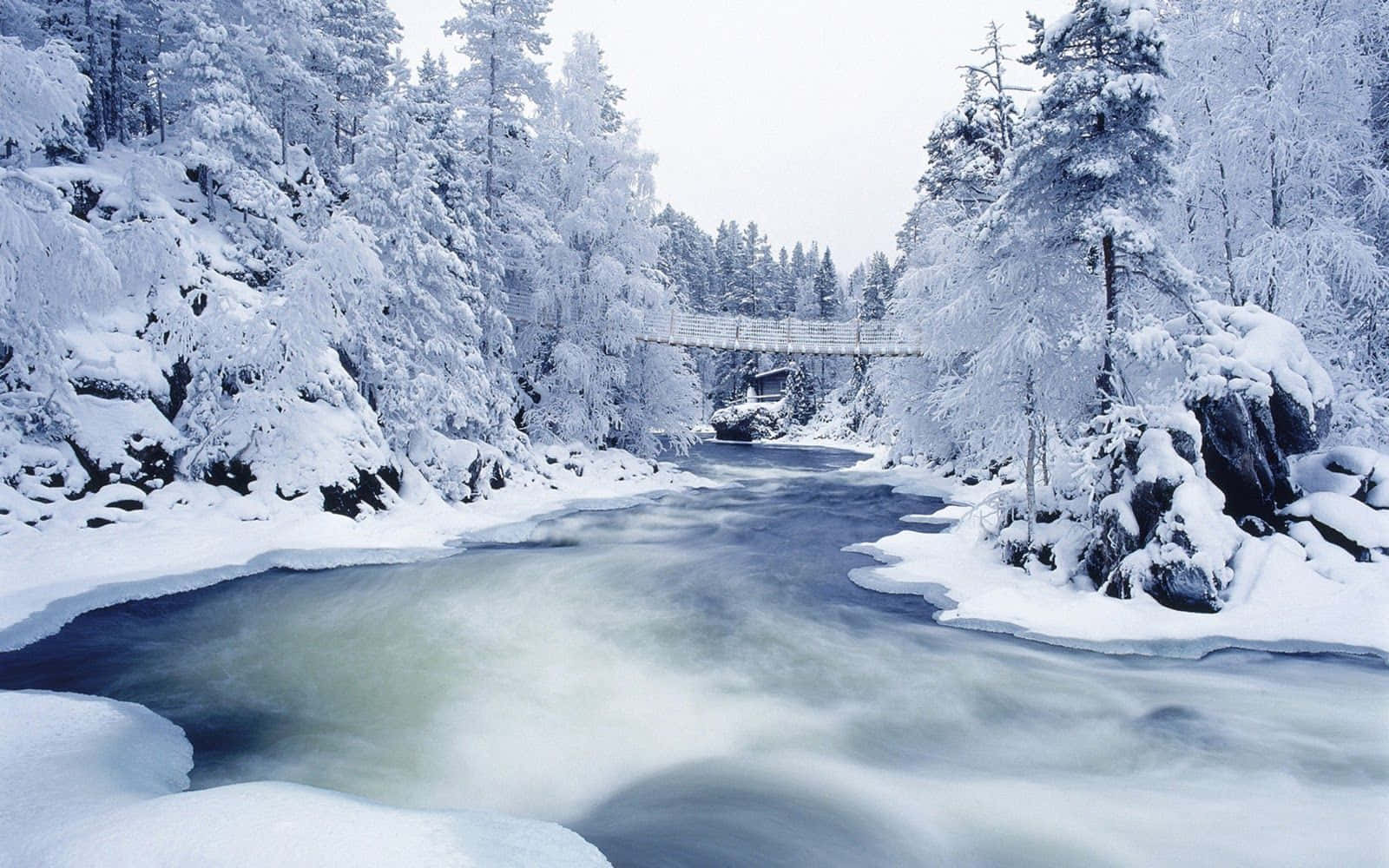 A Snow Covered River With A Bridge