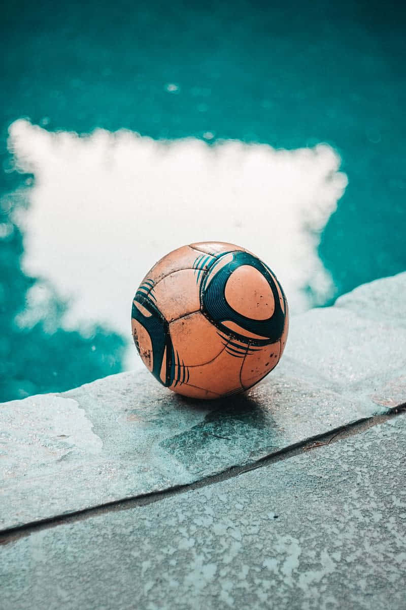 Weathered Soccer Ball Beside Pool Wallpaper