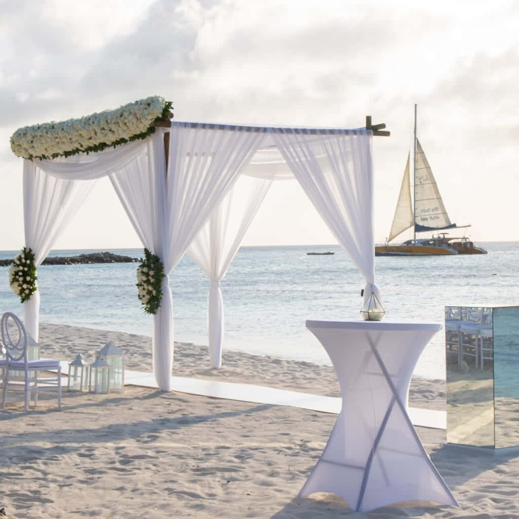 A Beach Wedding Ceremony With White Chairs And Tables