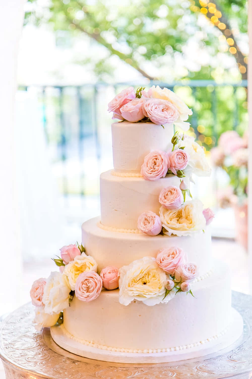 A White Wedding Cake With Pink Roses On Top