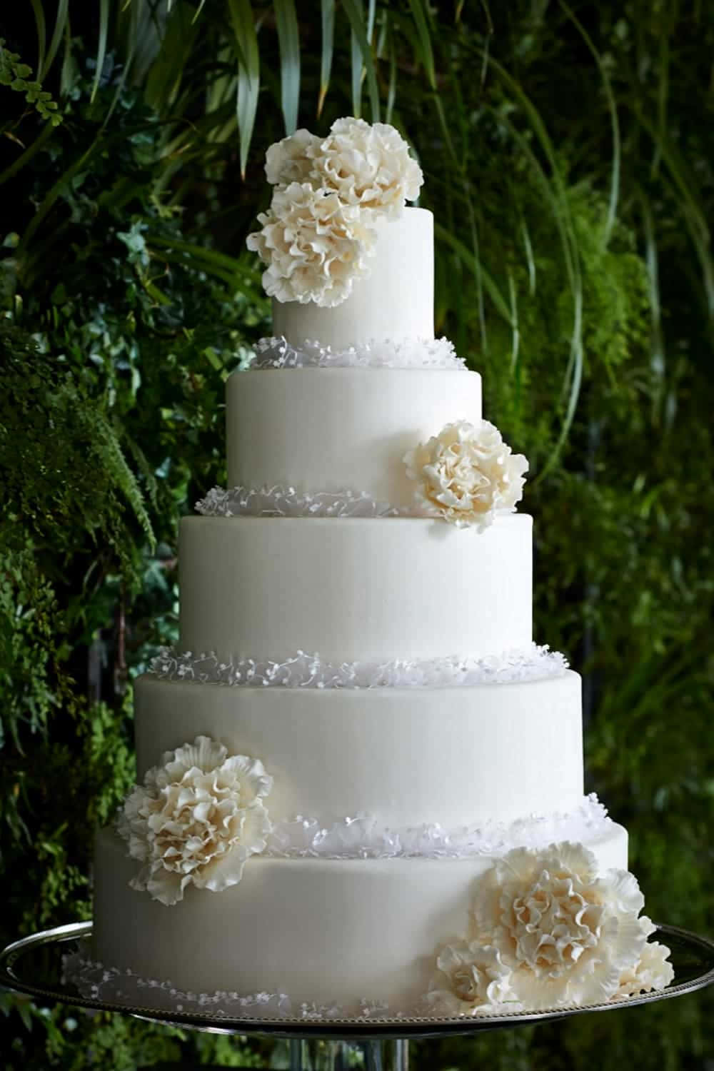 A White Wedding Cake With White Flowers On Top