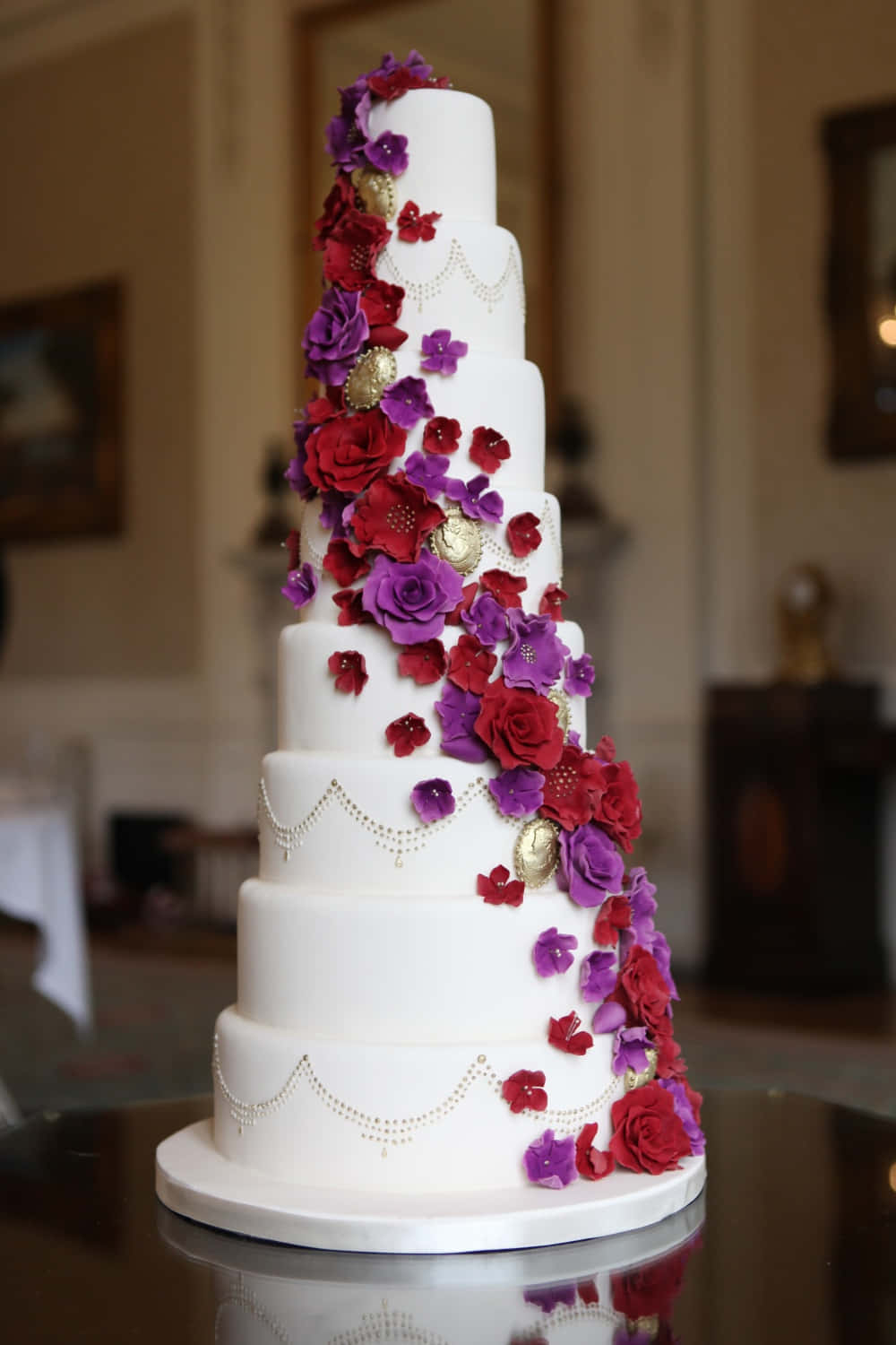 A White Wedding Cake With Purple And Red Flowers