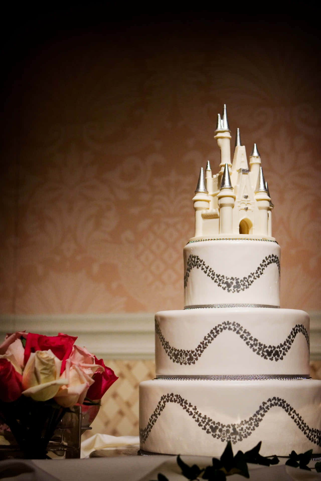 A decadent, three-tiered Wedding Cake adorned with roses and ivory drapes