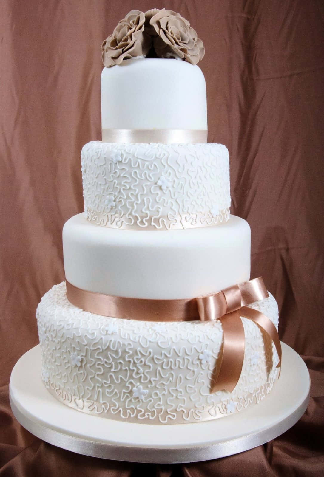 A White Wedding Cake With A Brown Ribbon
