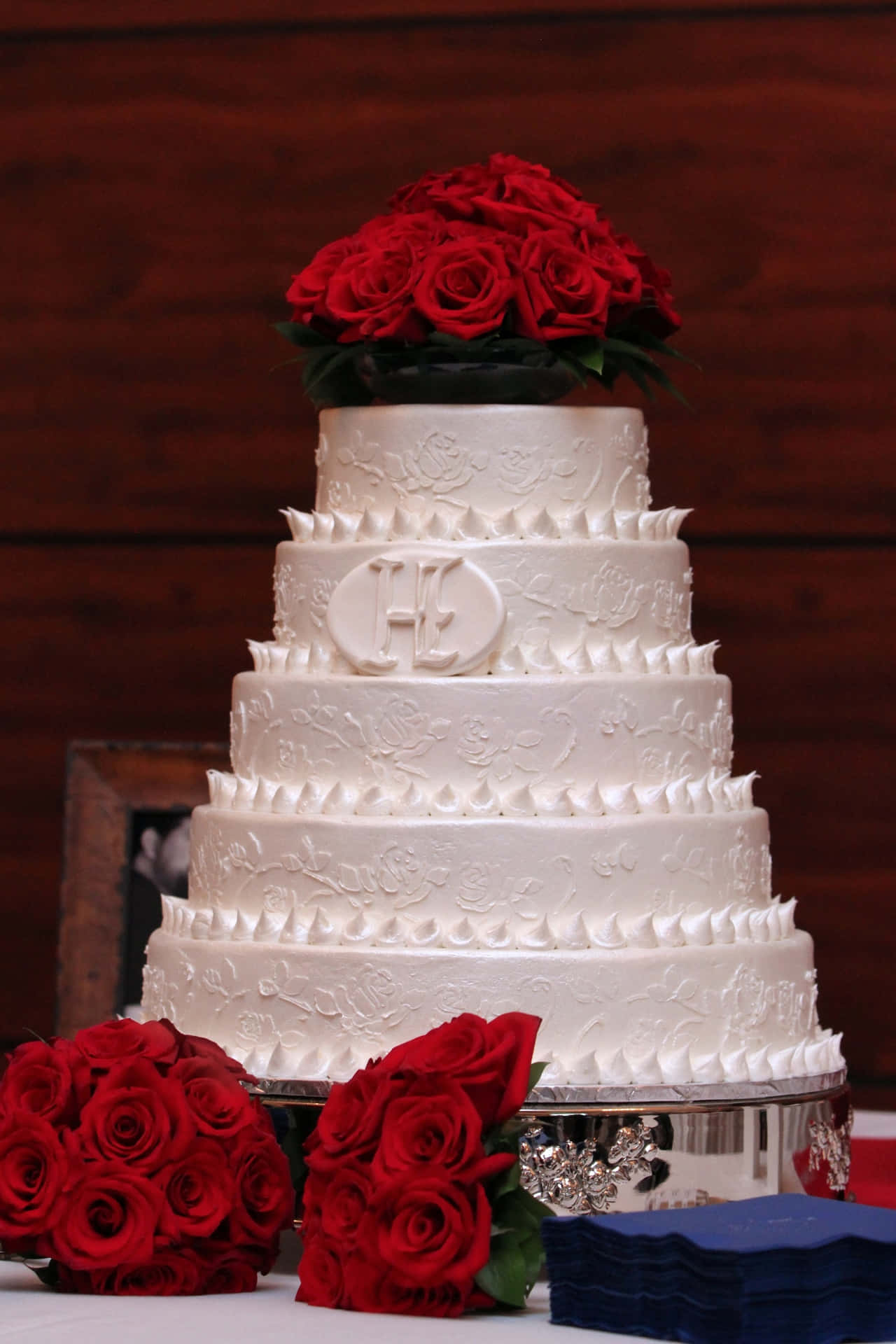 A White Wedding Cake With Red Roses On Top