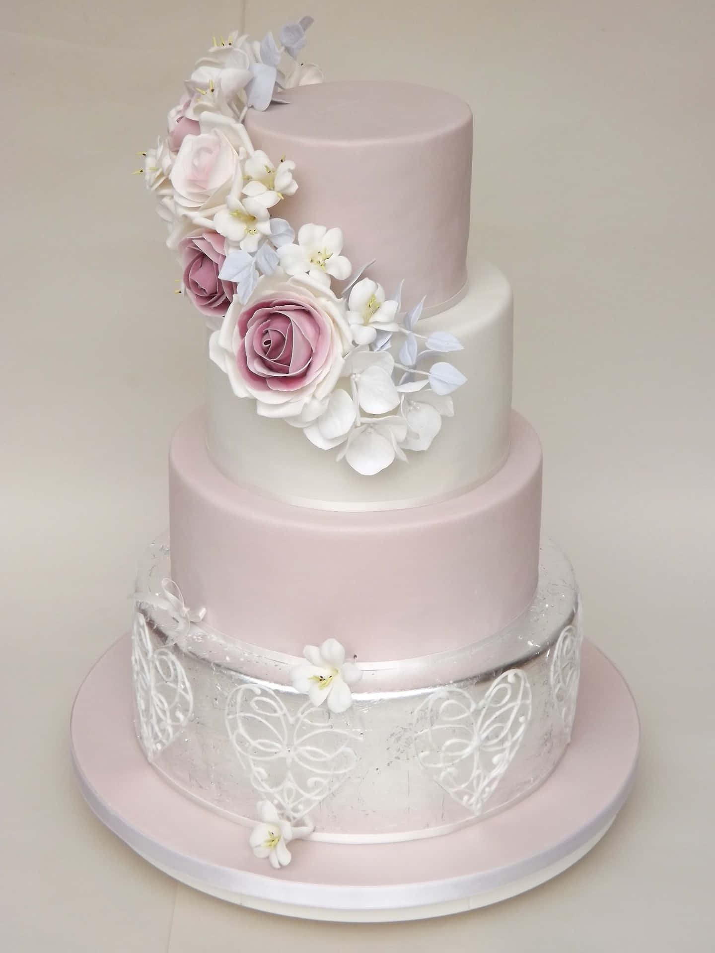 A Three Tier Cake With Pink Flowers And Silver Decorations