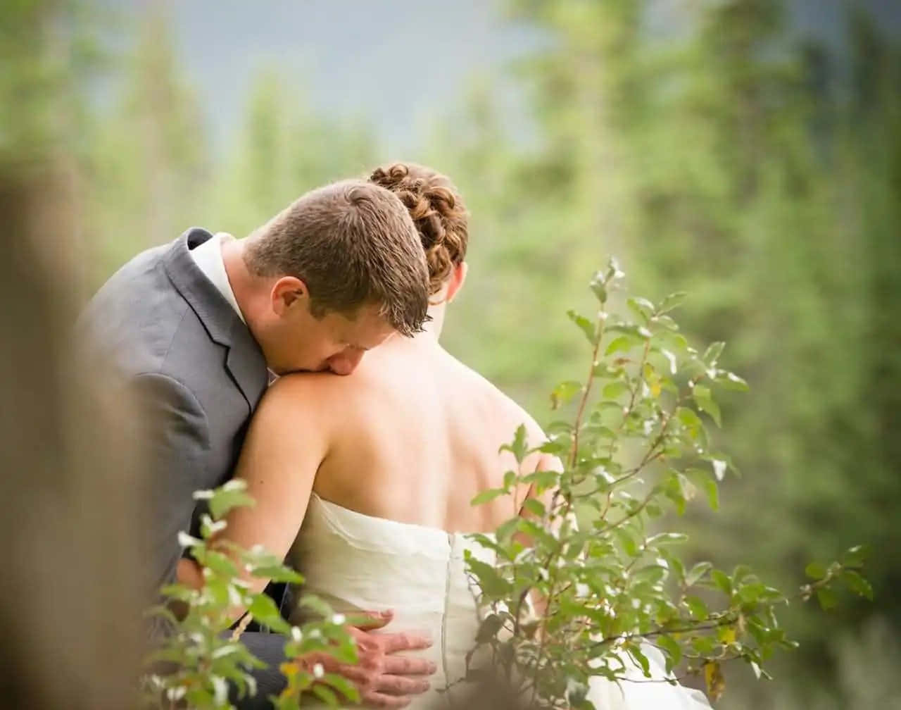 A beautiful, romantic wedding couple embracing under a rose garden trellis.