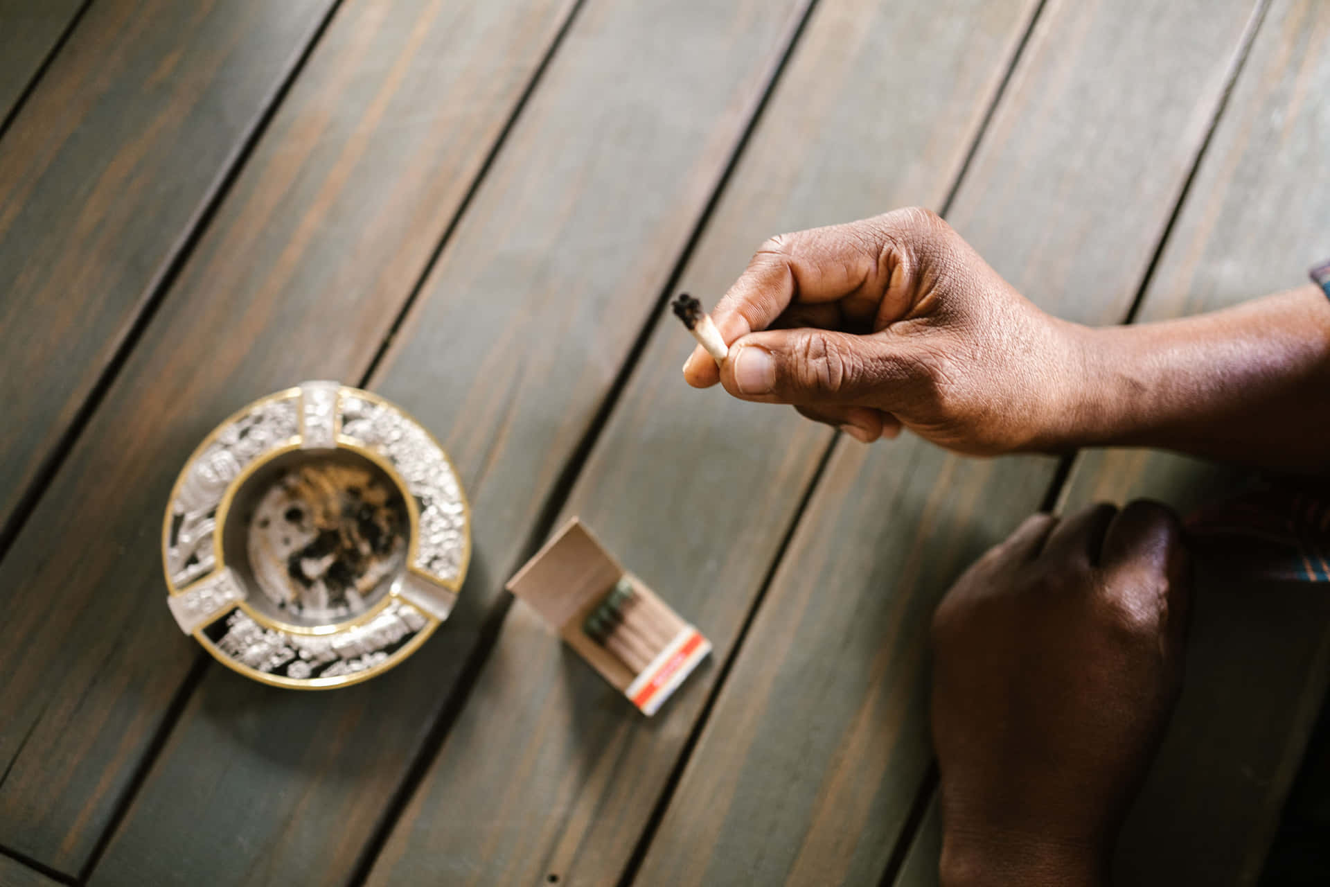 Unhombre Está Fumando Un Cigarrillo En Una Mesa De Madera. Fondo de pantalla