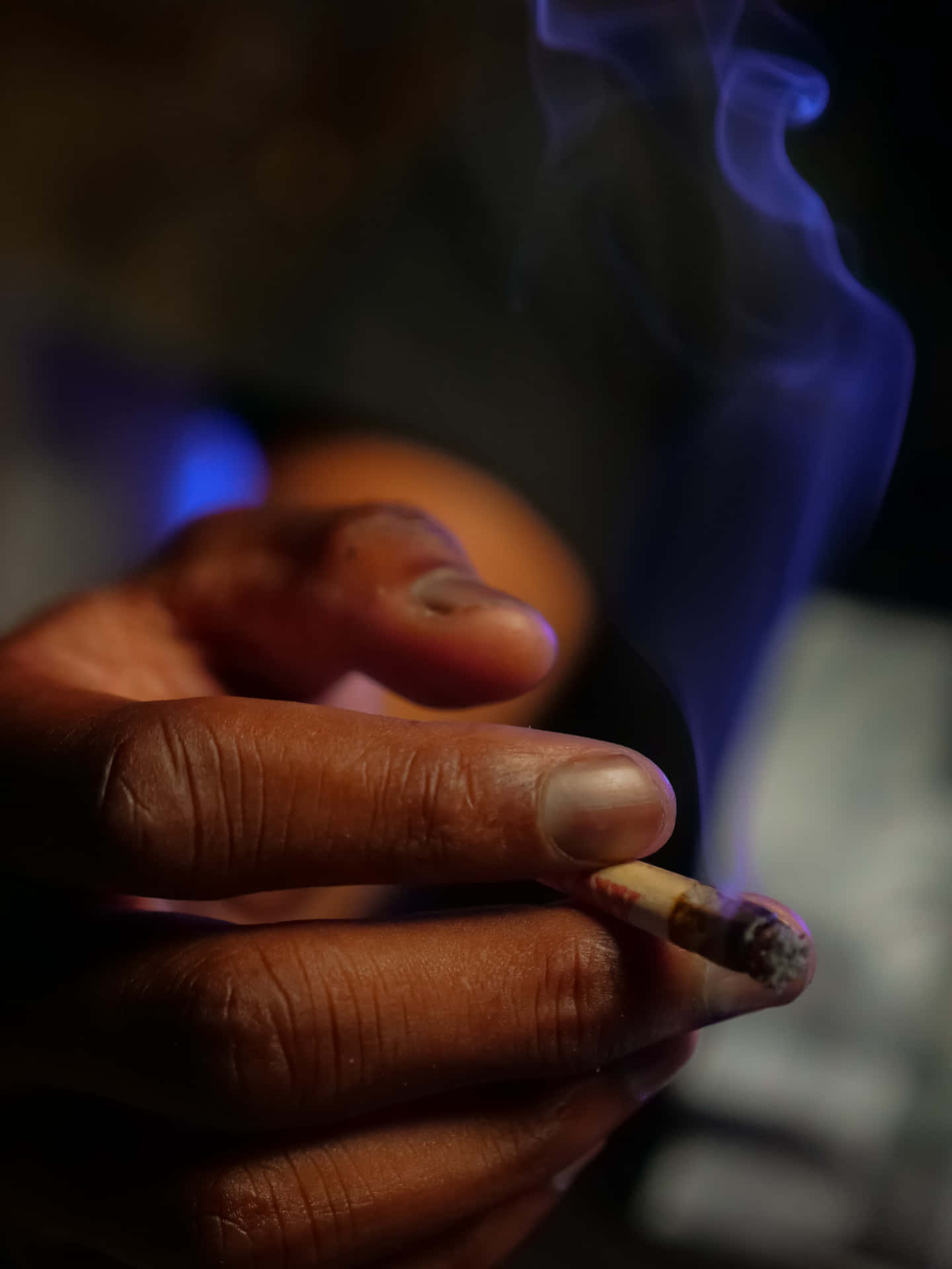 Unapersona Está Fumando Un Cigarrillo En Una Habitación Oscura. Fondo de pantalla
