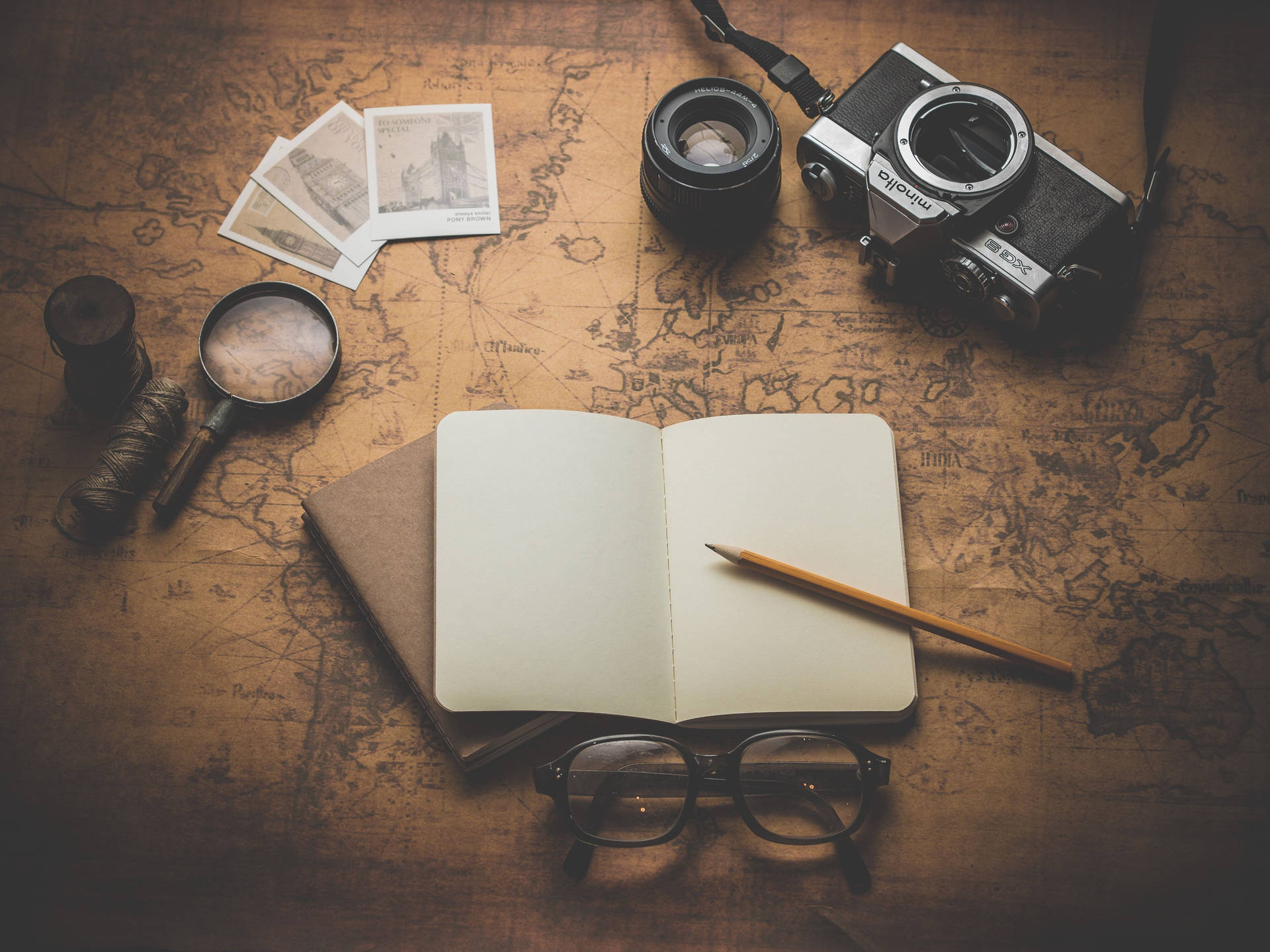 A Notebook, Camera, Magnifying Glass And Map On A Wooden Table Wallpaper
