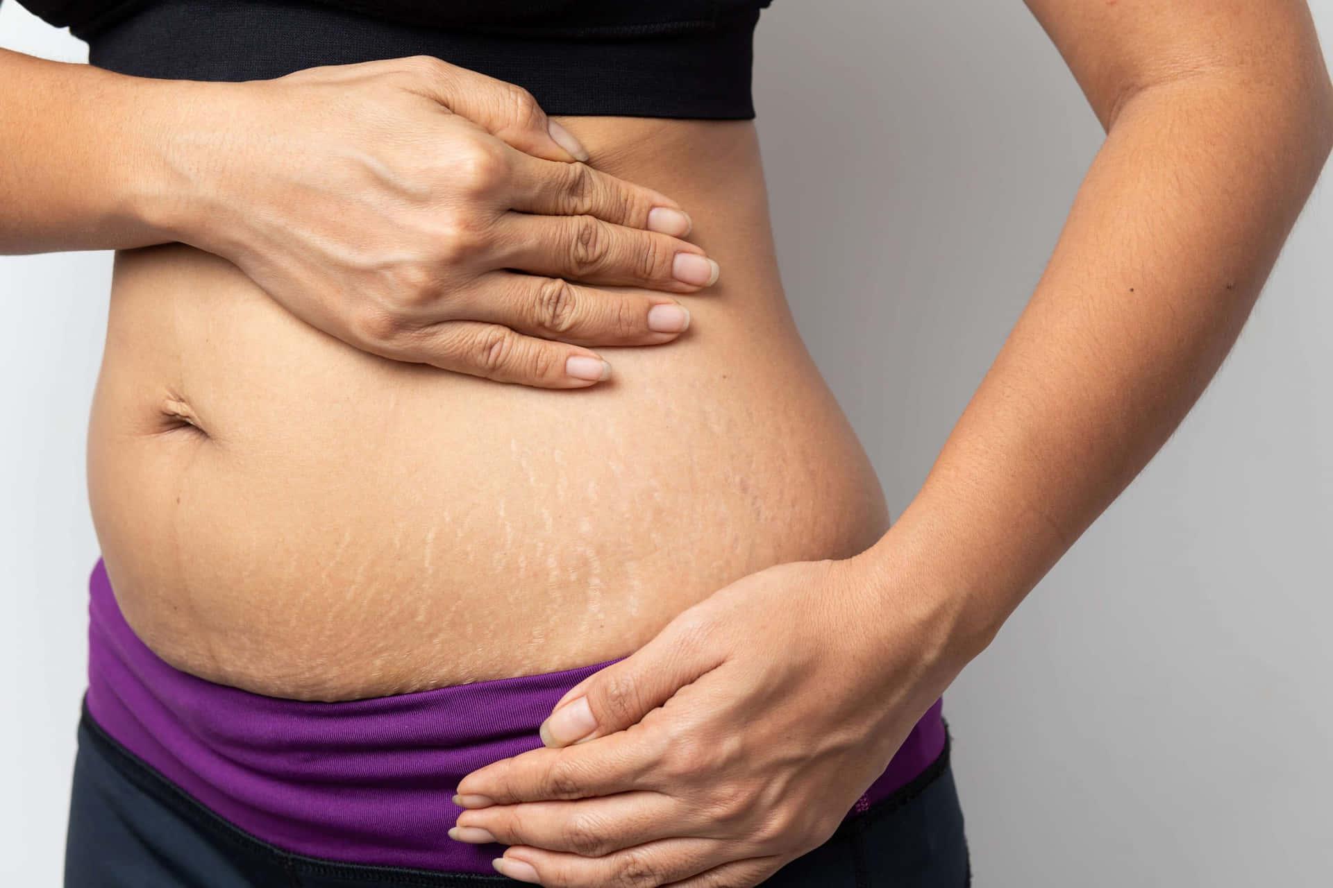 A Woman Is Holding Her Stomach With Her Hands