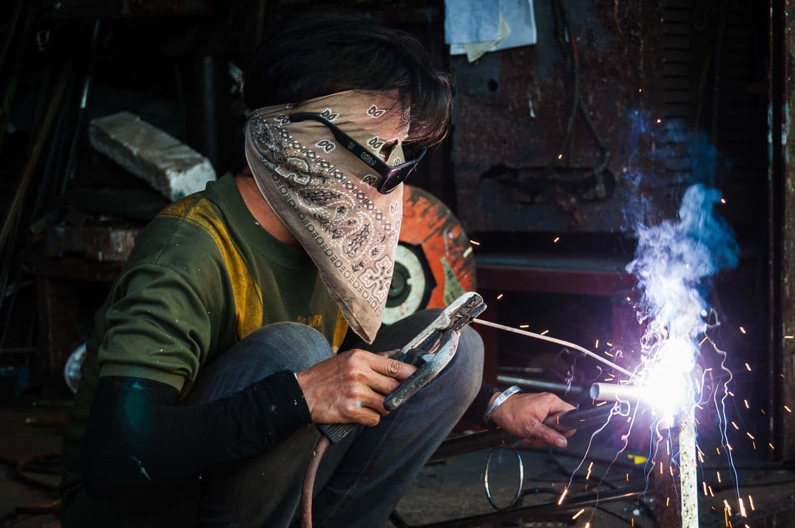 A Man Welding In A Workshop With Sparks Wallpaper