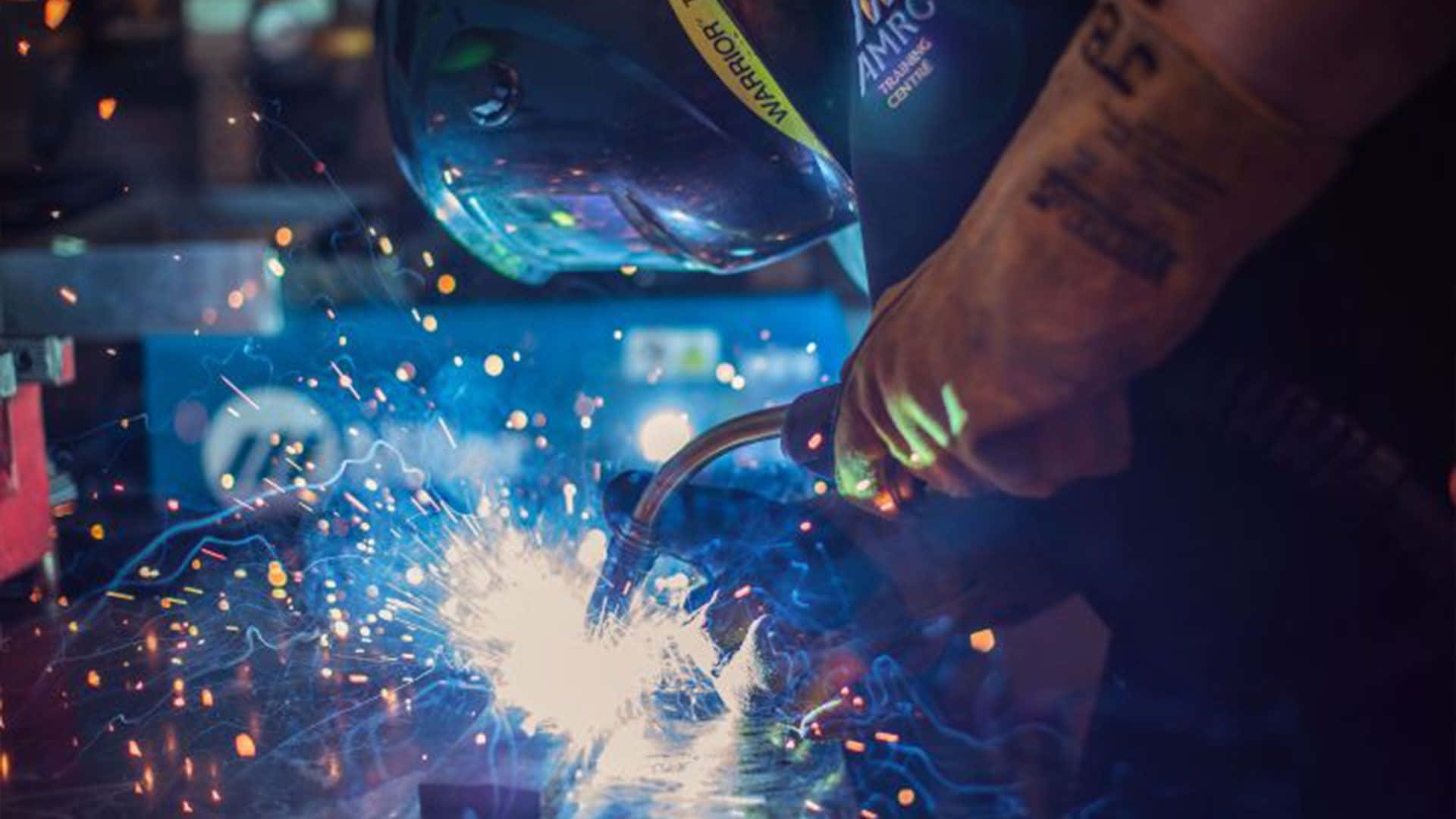 A Person Welding With Sparks In His Helmet Wallpaper