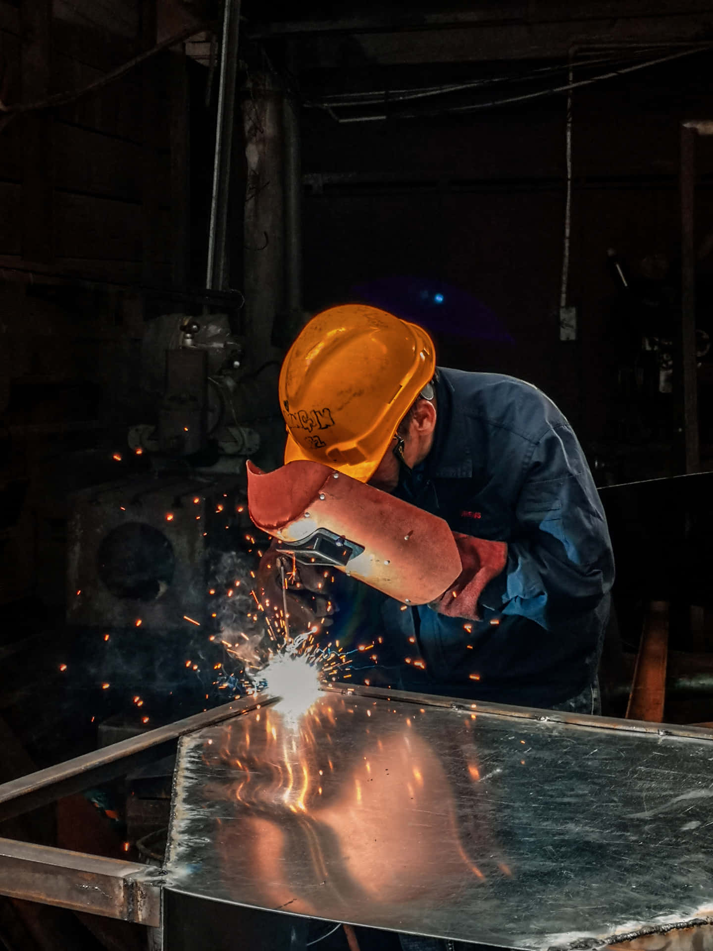 En mand svejsning metal i en brændende fabrik Wallpaper