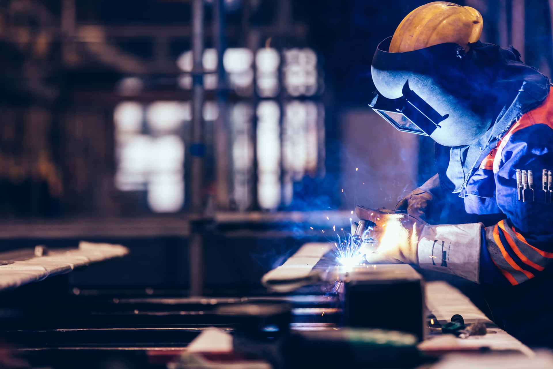 A Worker Welding Metal In A Factory Wallpaper