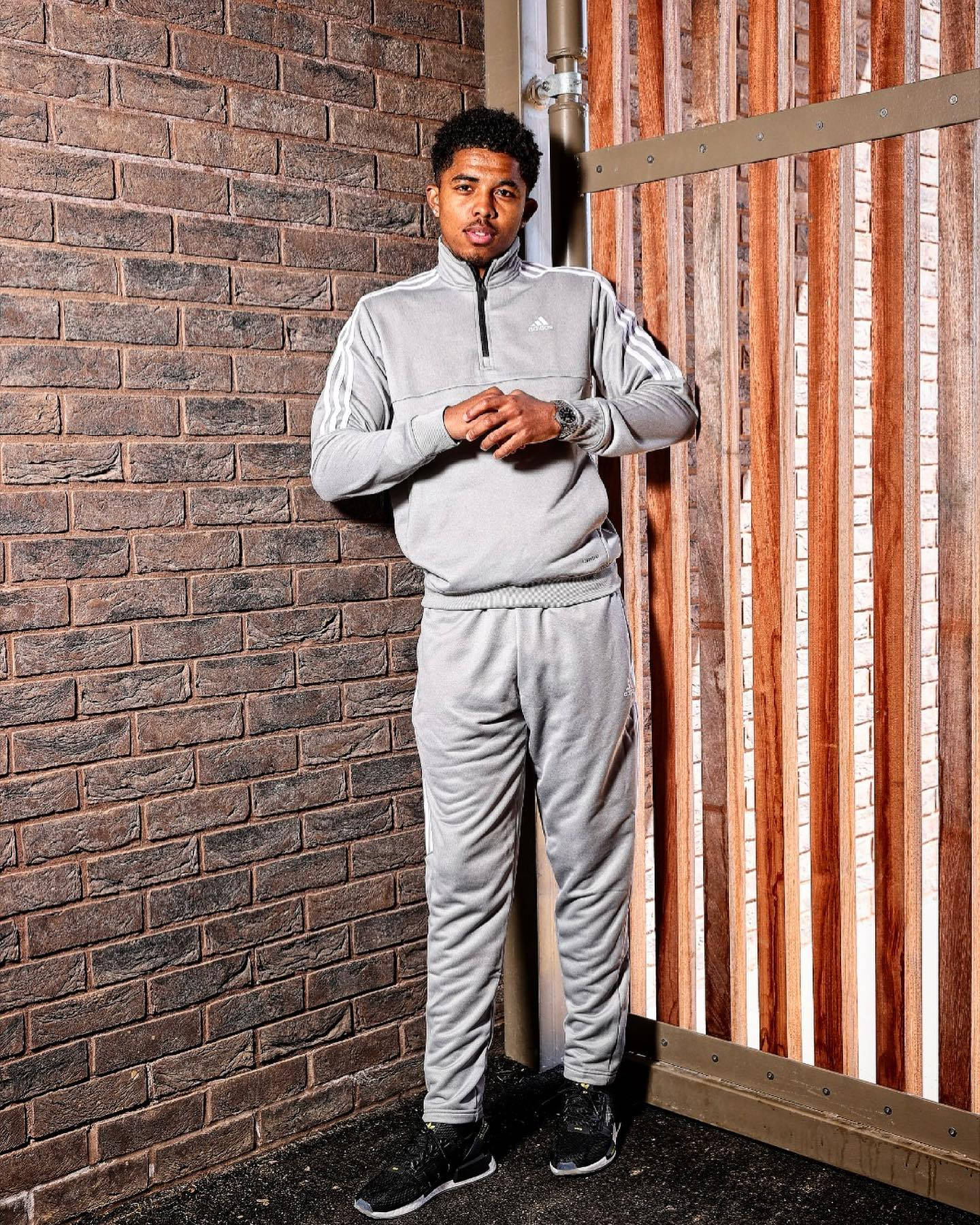 A man in louis vuitton tracksuit standing and leaning against the wall