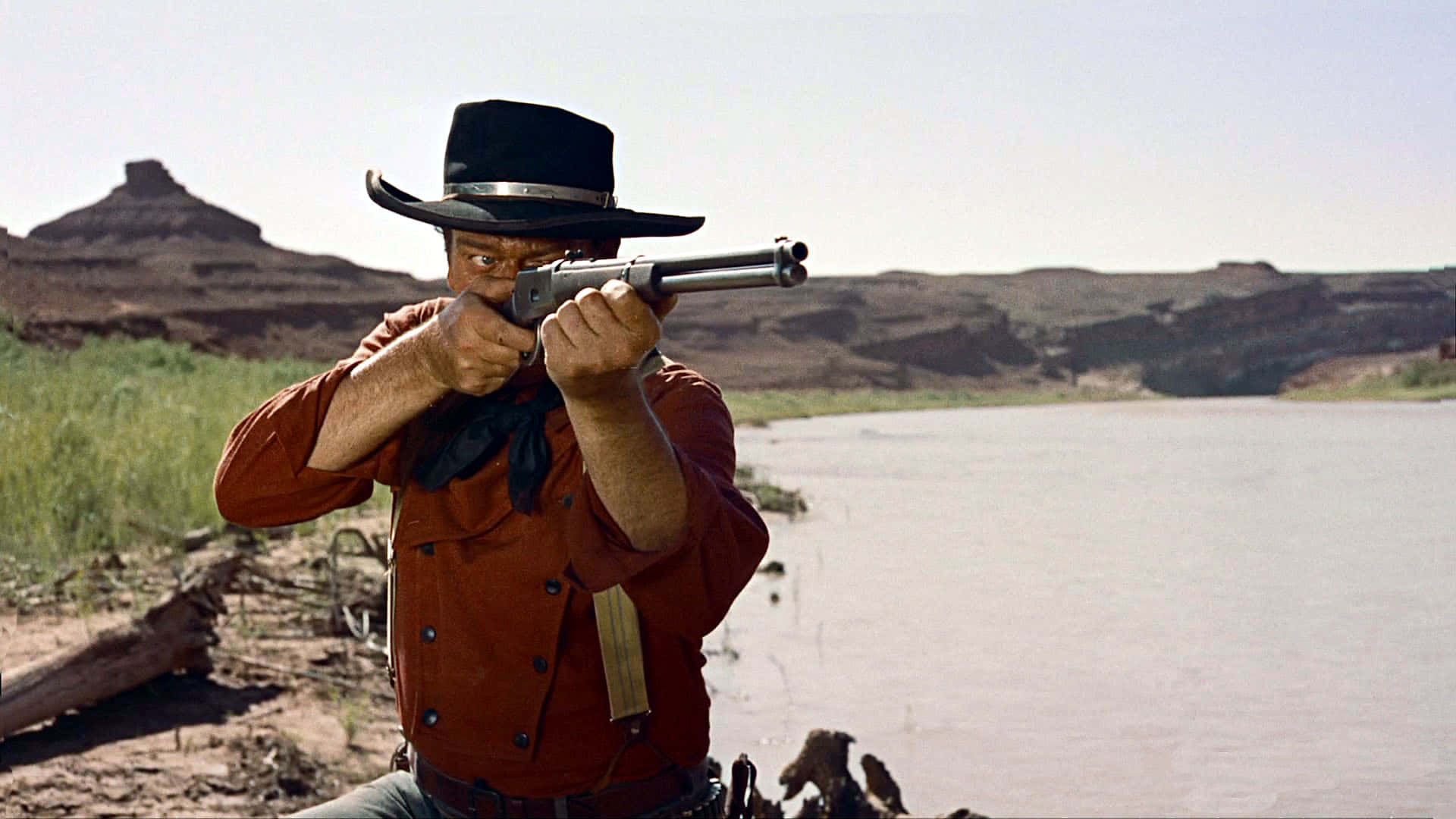 A Man In A Cowboy Hat Is Holding A Gun Wallpaper