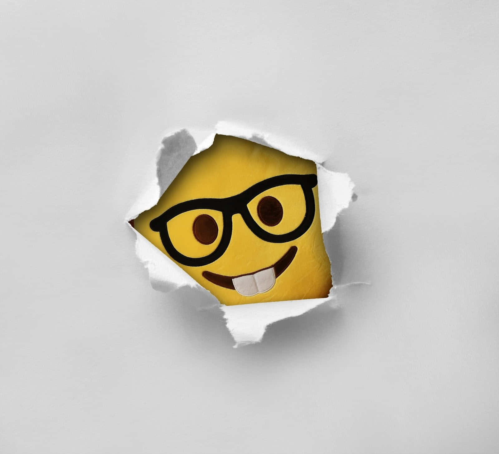 A Smiling Emoji Face Is Peeking Out Of A Piece Of Paper