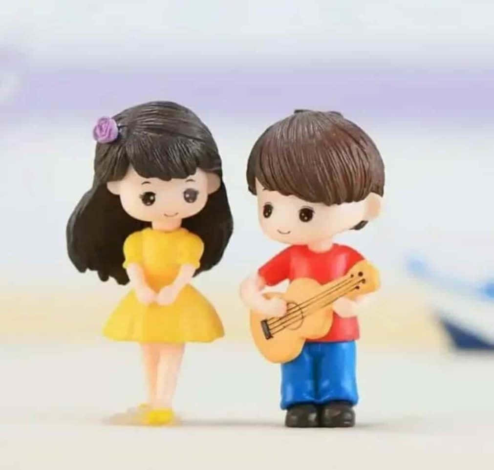 Two Figurines Of A Boy And Girl Playing Guitar