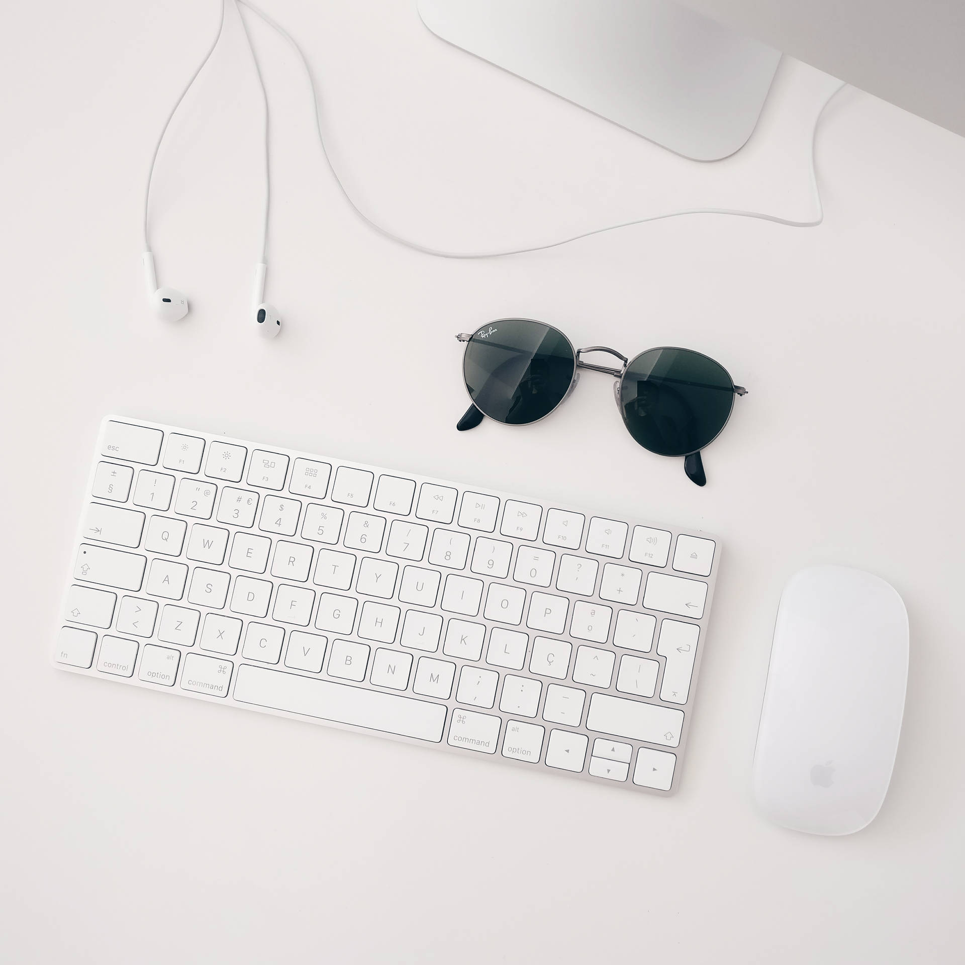 Minimalist wallpaper of white Apple MAC set-up consisting of iMAC, wireless keyboard, magic mouse and earphone.