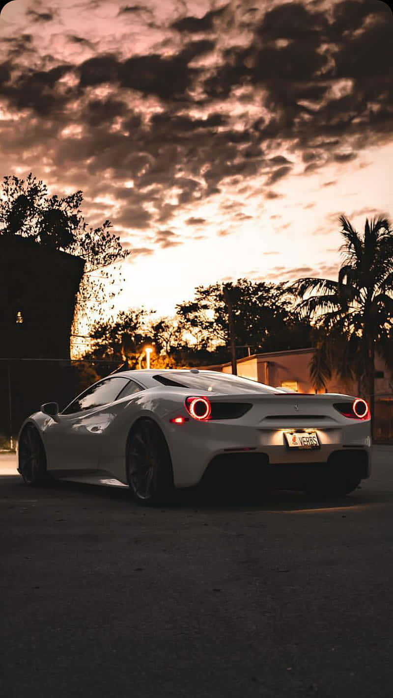 A White Sports Car Parked In The Street At Sunset Wallpaper