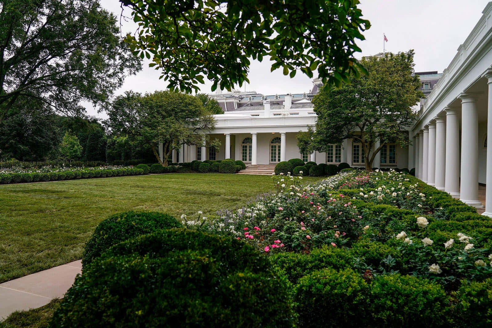 The White House Has A Large Lawn With Trees And Flowers