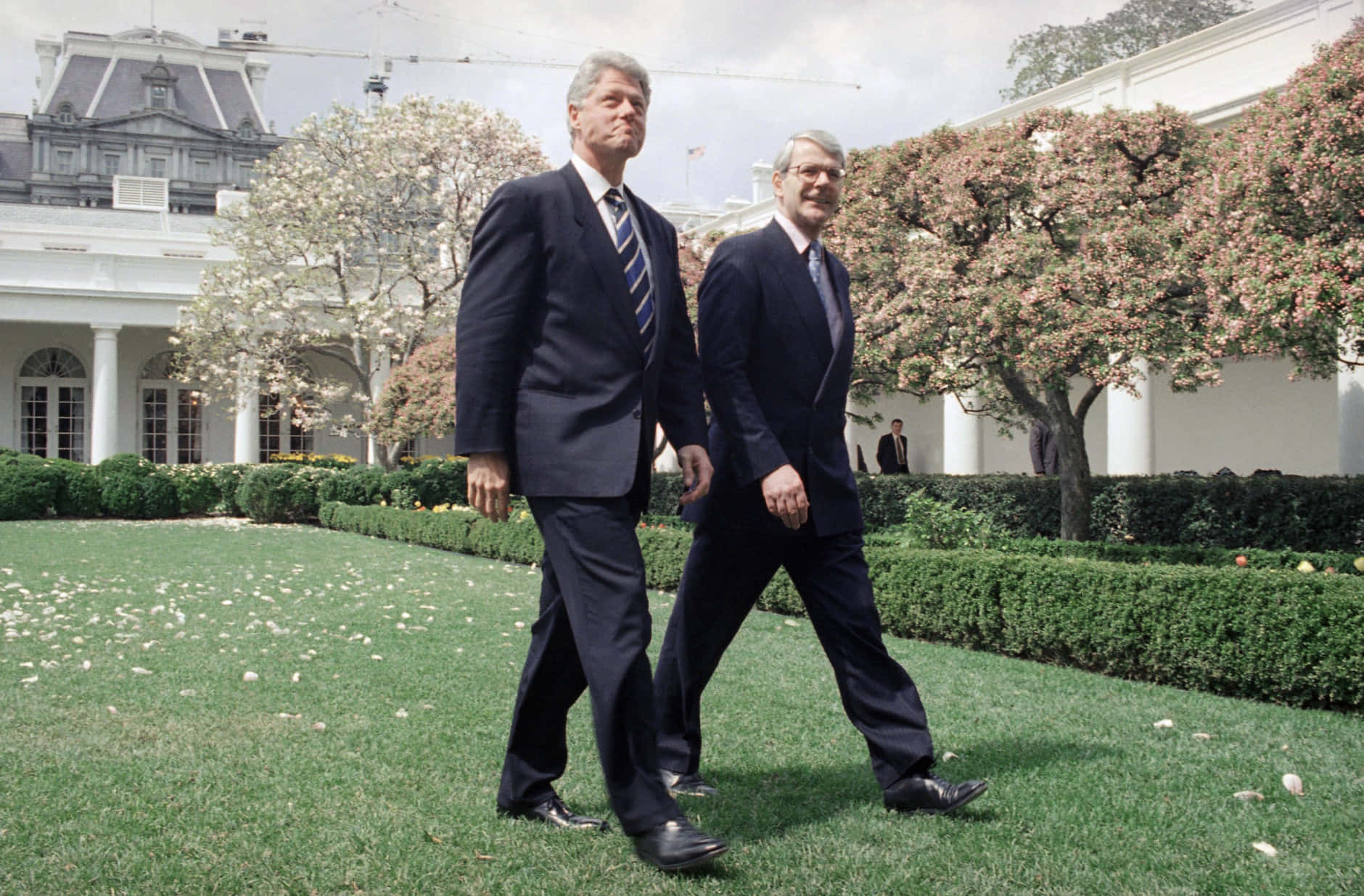 Two Men Walking In Front Of A White House