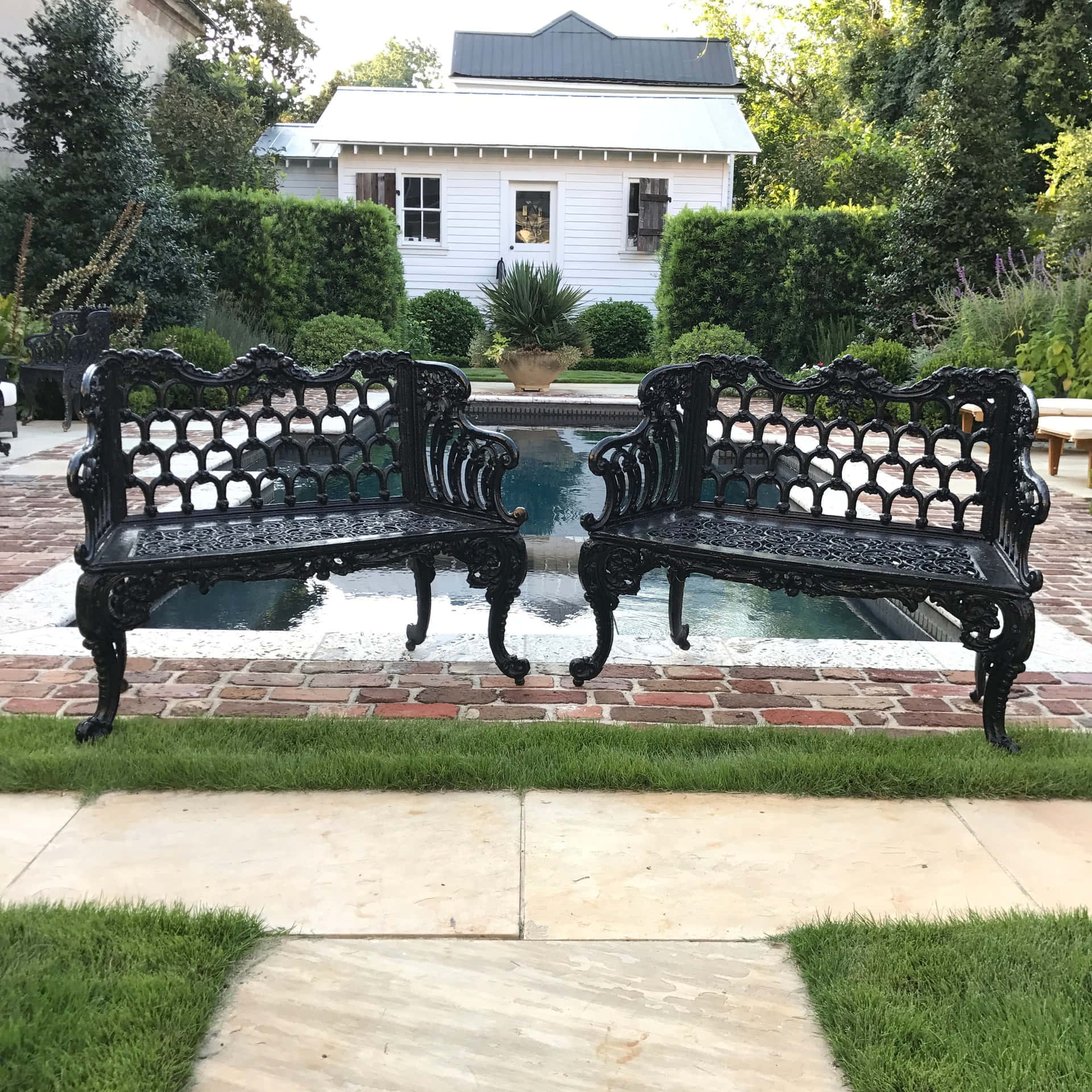 Two Black Iron Benches In Front Of A Pool