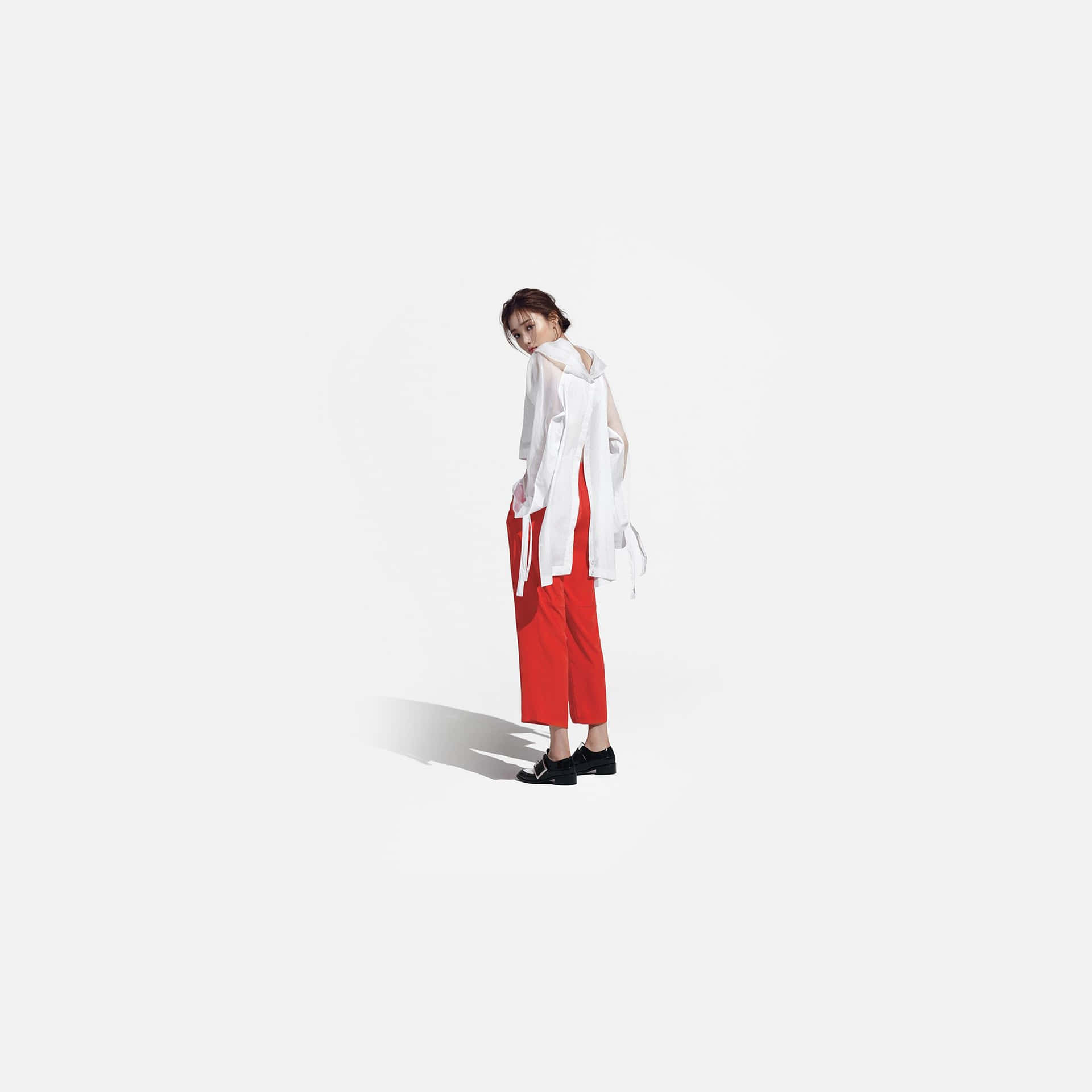 En kvinde i røde bukser står på en hvid baggrund Wallpaper
