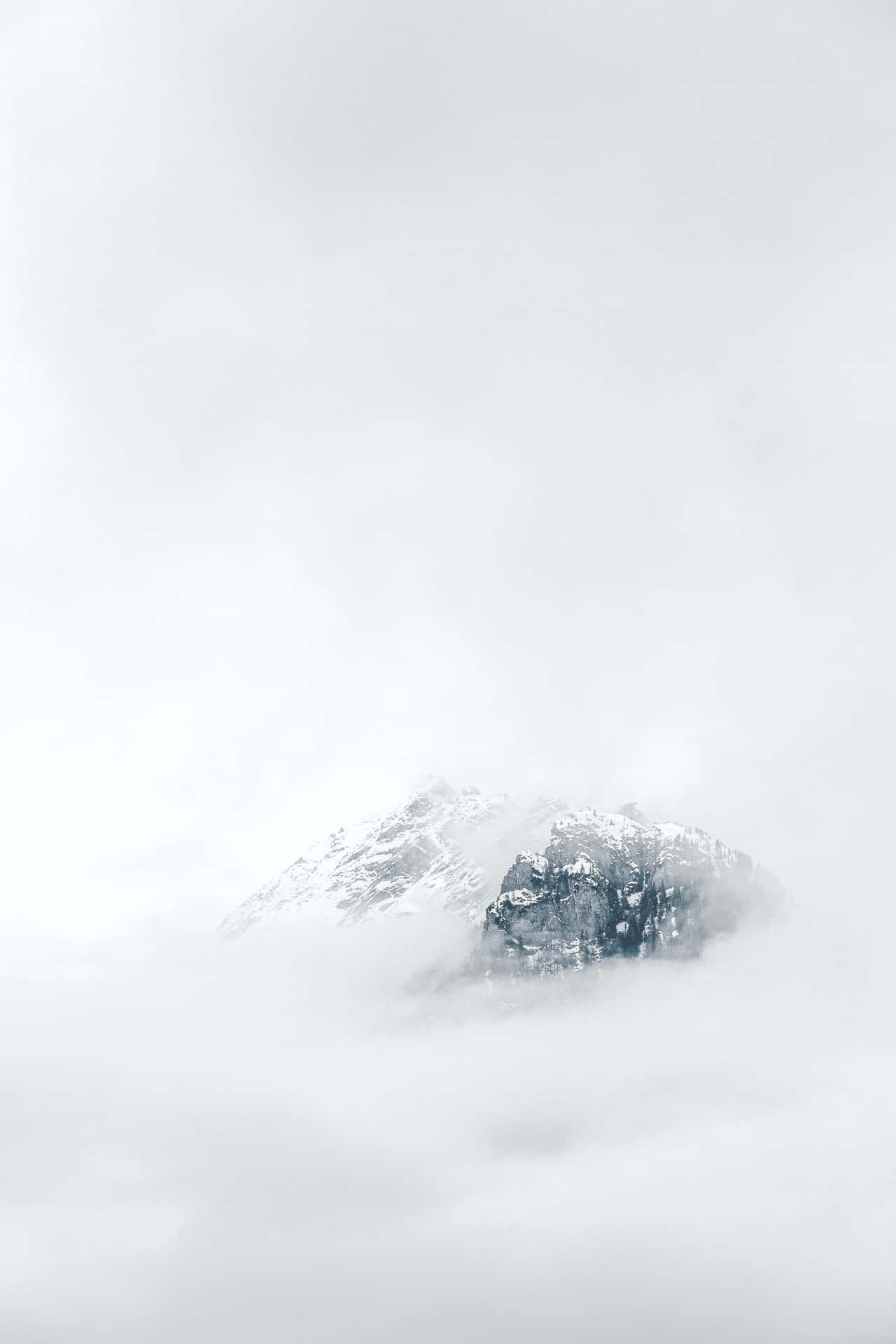 A Mountain Covered In Clouds With Snow On Top