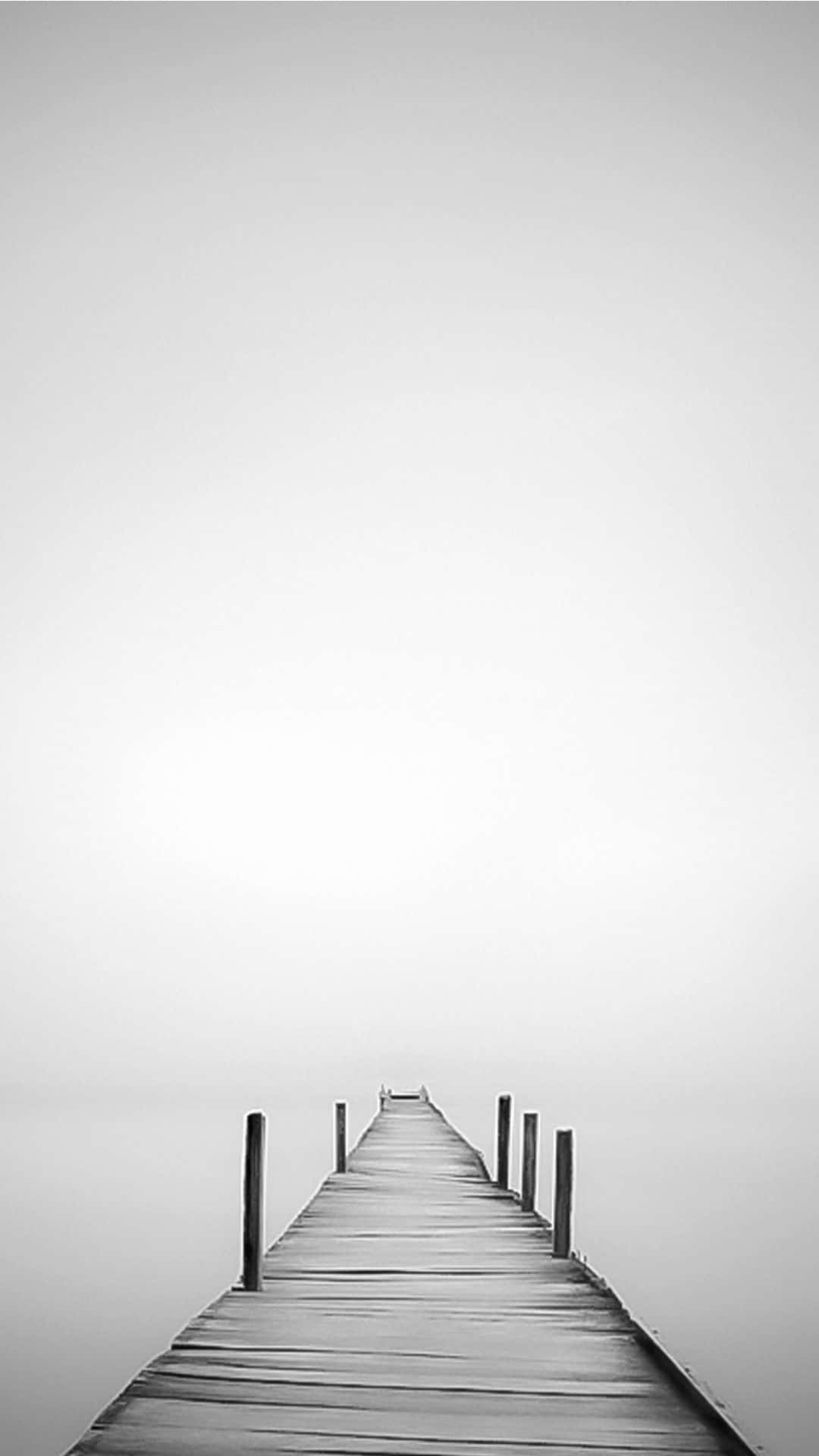 A Black And White Photo Of A Pier In The Fog