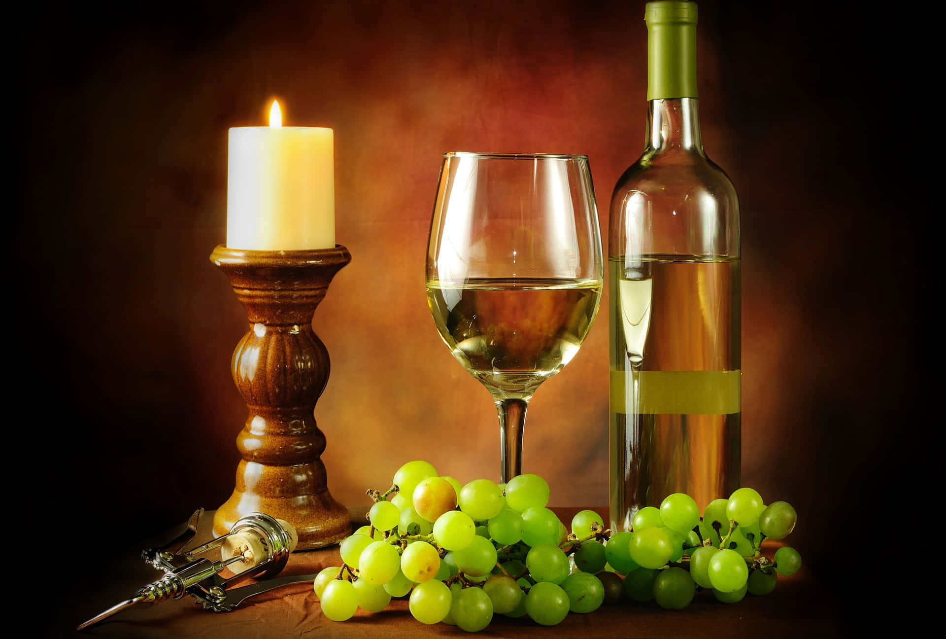 A chilled glass of white wine surrounded by bunches of green and yellow grapes. Wallpaper