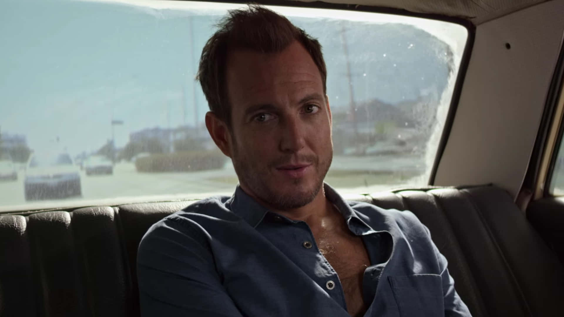 Will Arnett strikes a thoughtful pose against a sleek black background Wallpaper