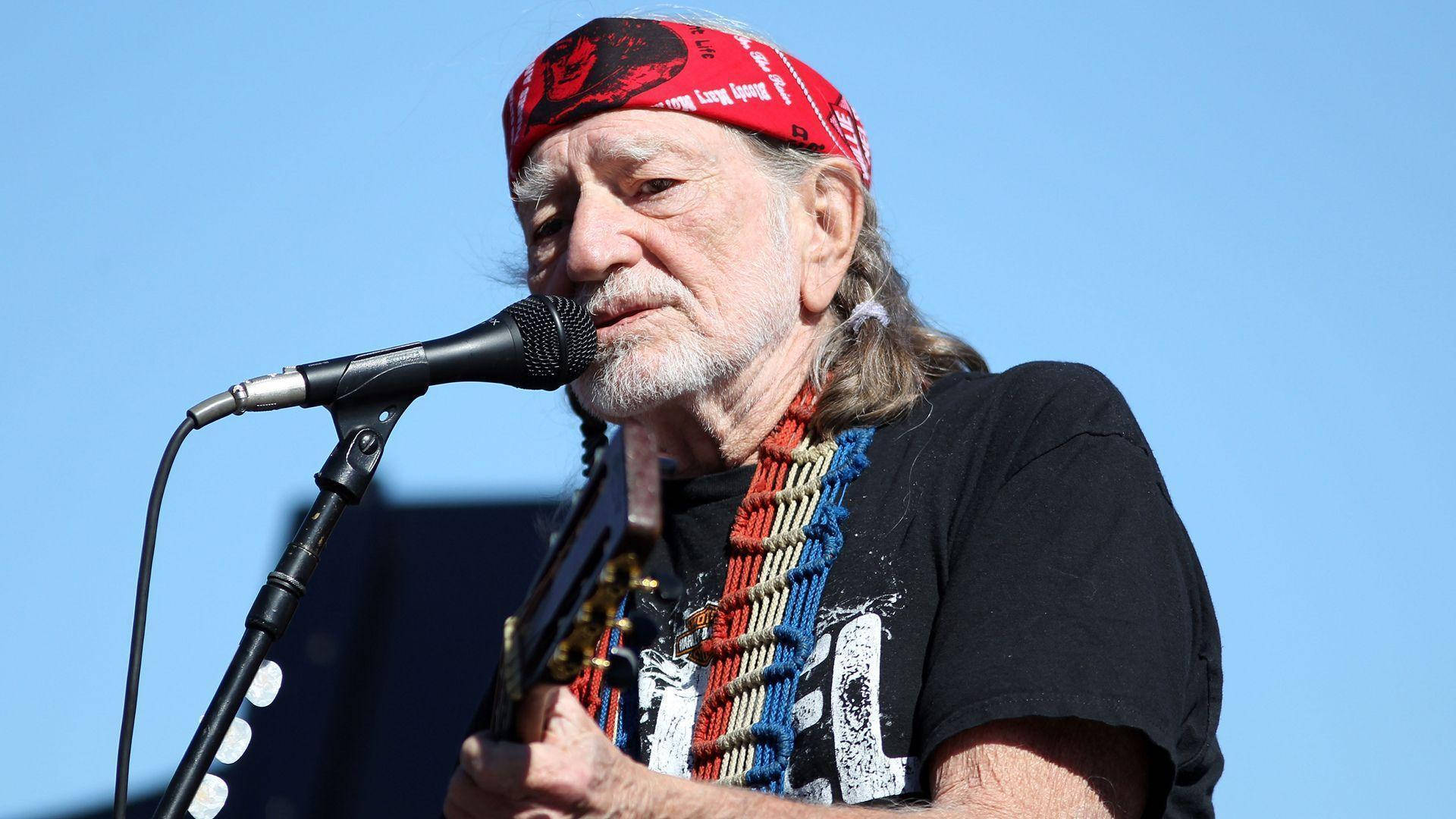 Willie Nelson Singing While Playing Guitar Wallpaper