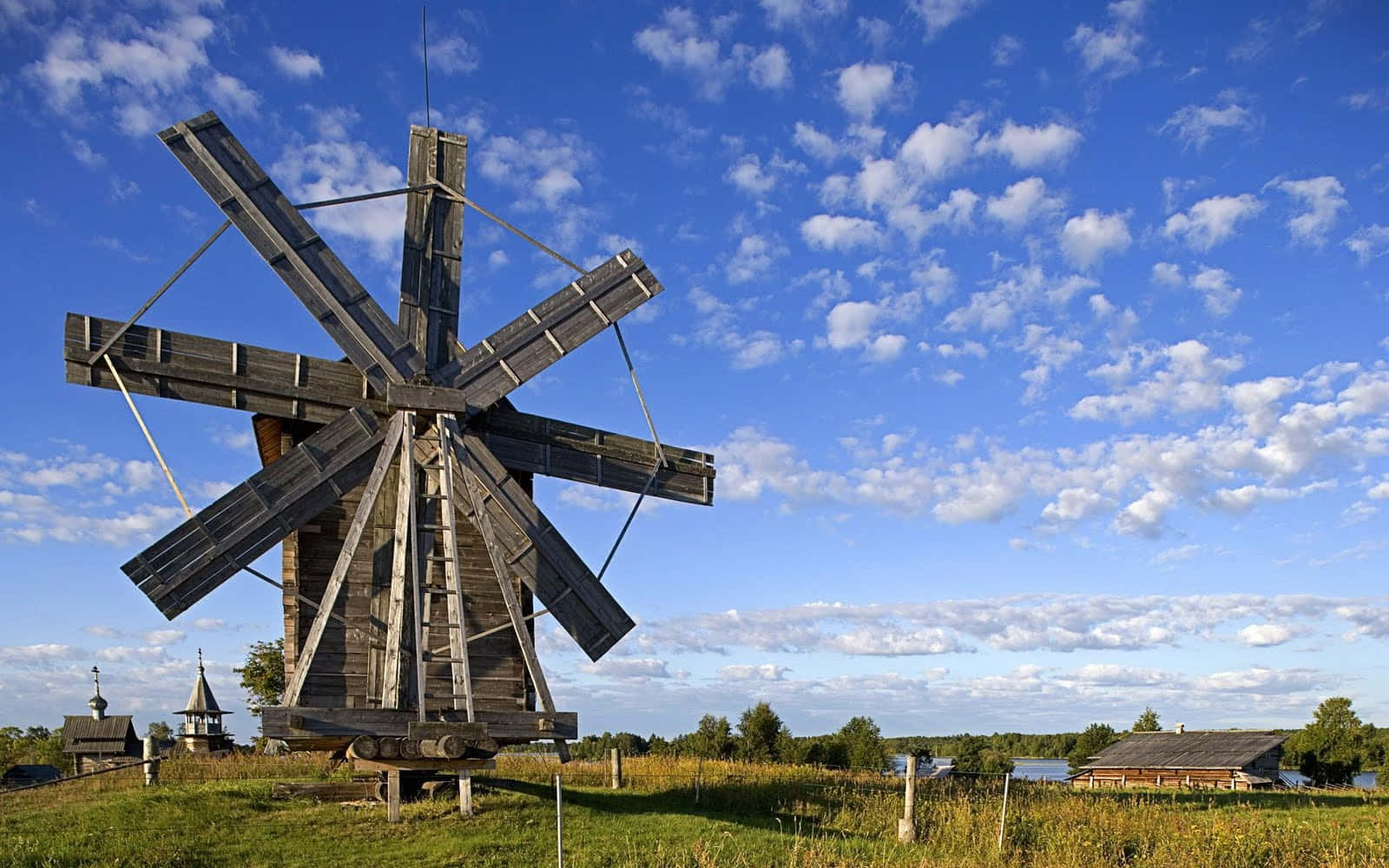 A Wooden Windmill Is Standing In A Field