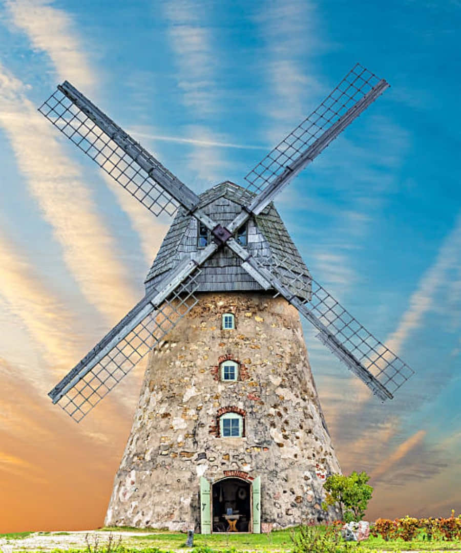 A rustic windmill that stands tall amidst an expanse of green pastures