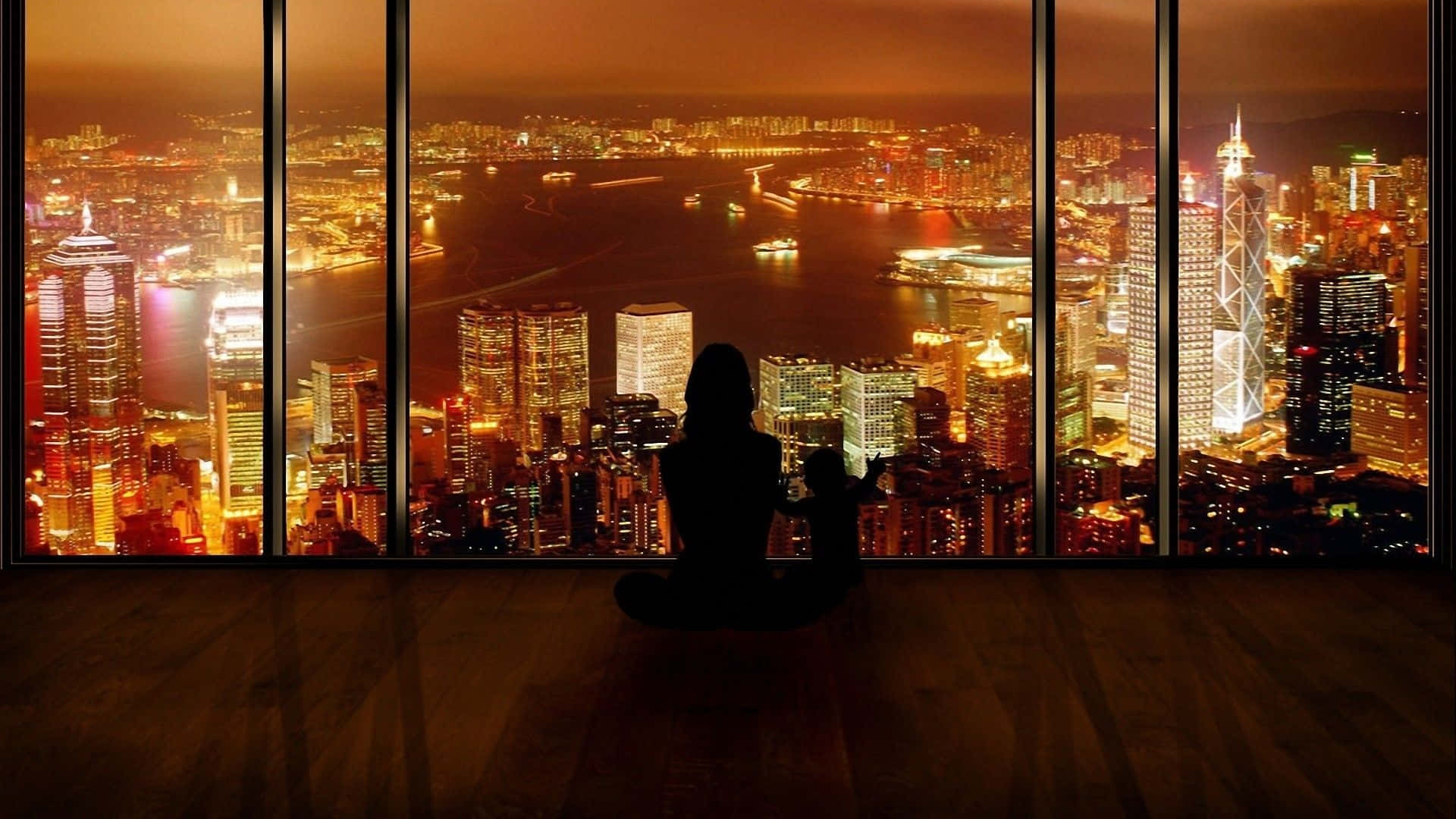 En kvinde sidder foran et vindue og ser på byens skyline.