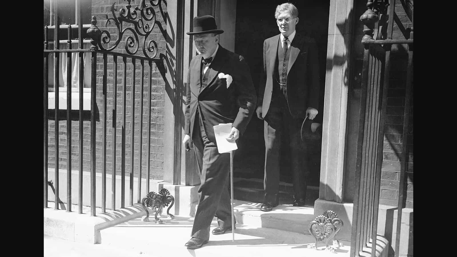 Two Men In Suits Standing Outside Of A Door
