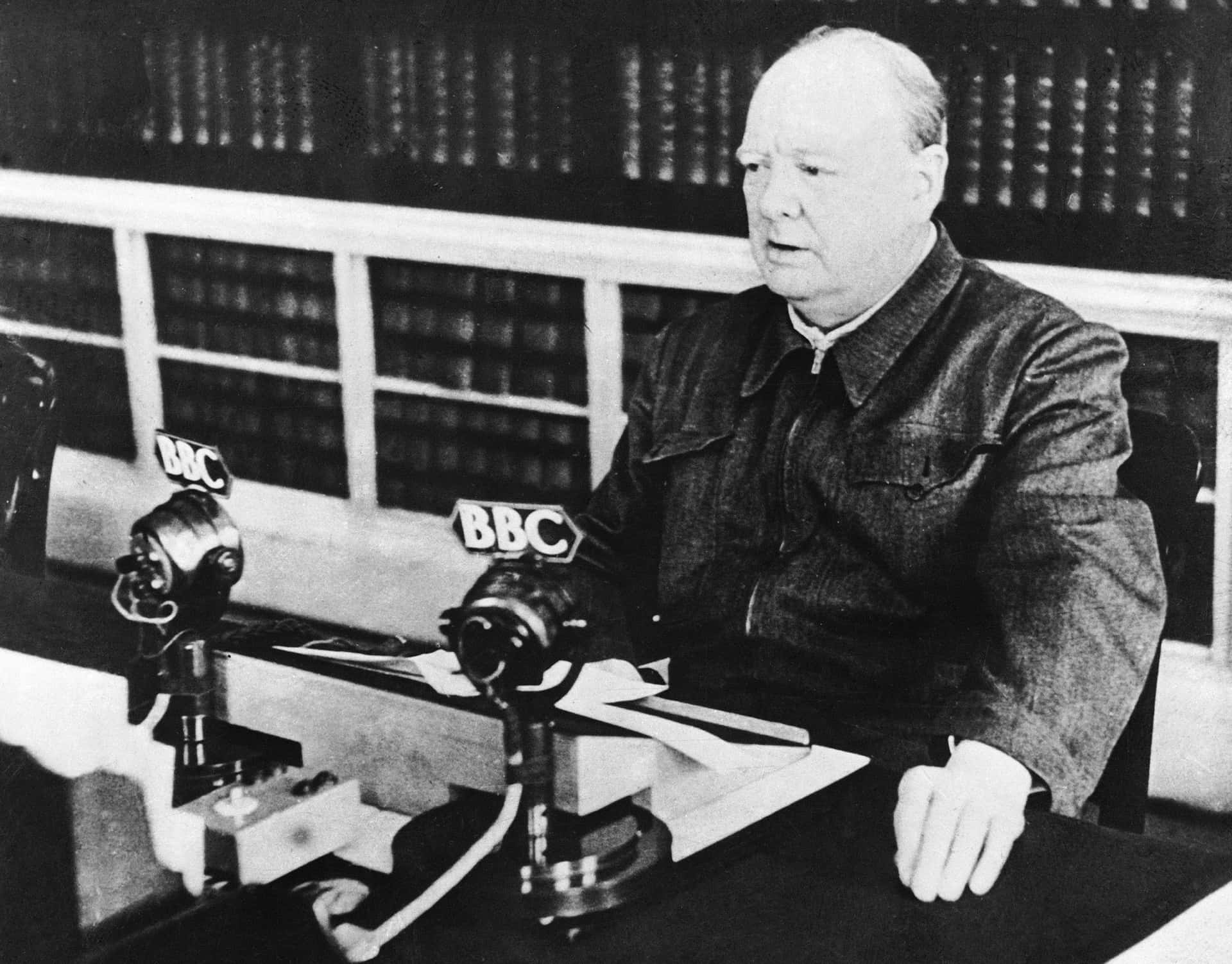 A Man Sitting At A Desk With Microphones