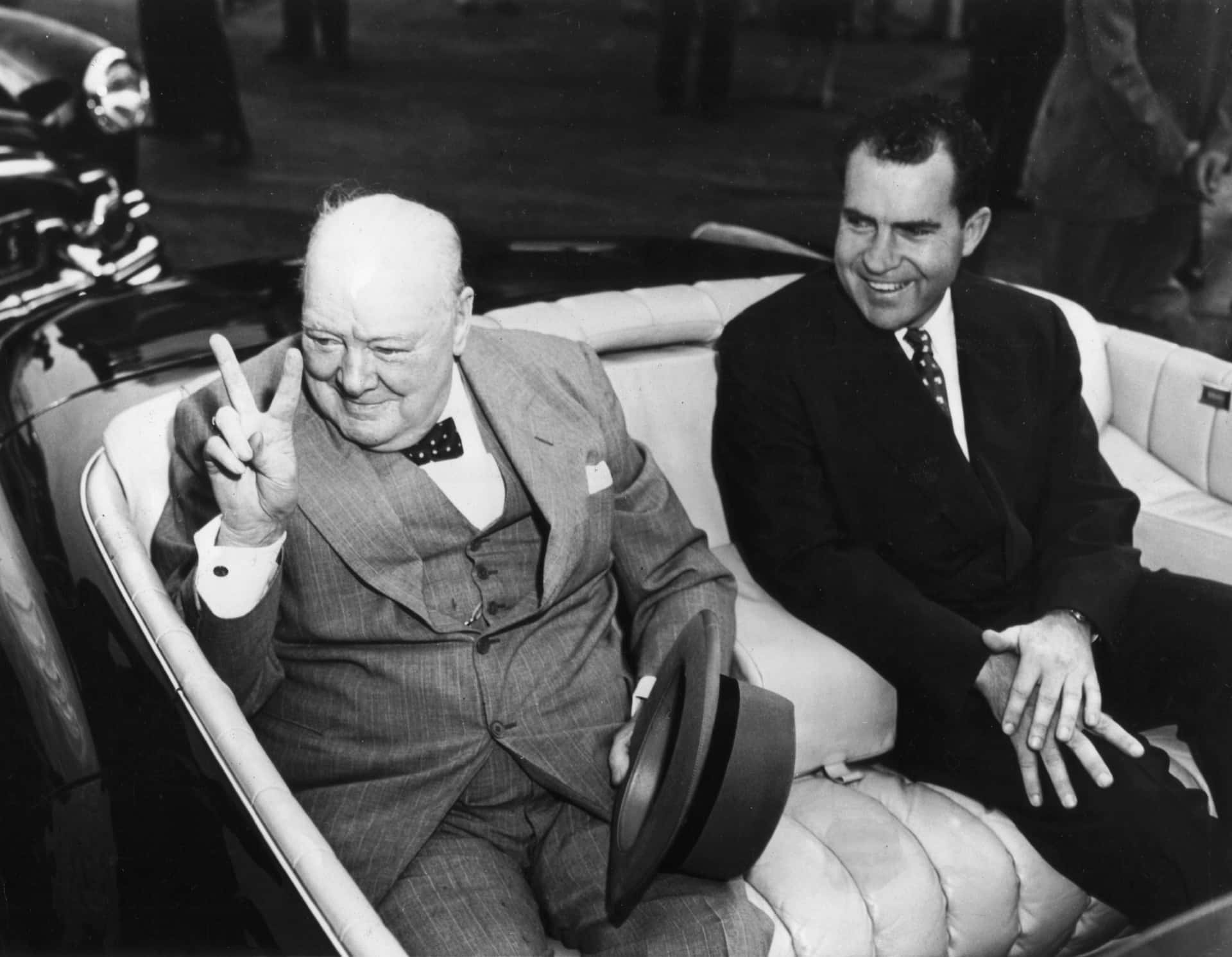 Two Men In Suits Sitting In A Car
