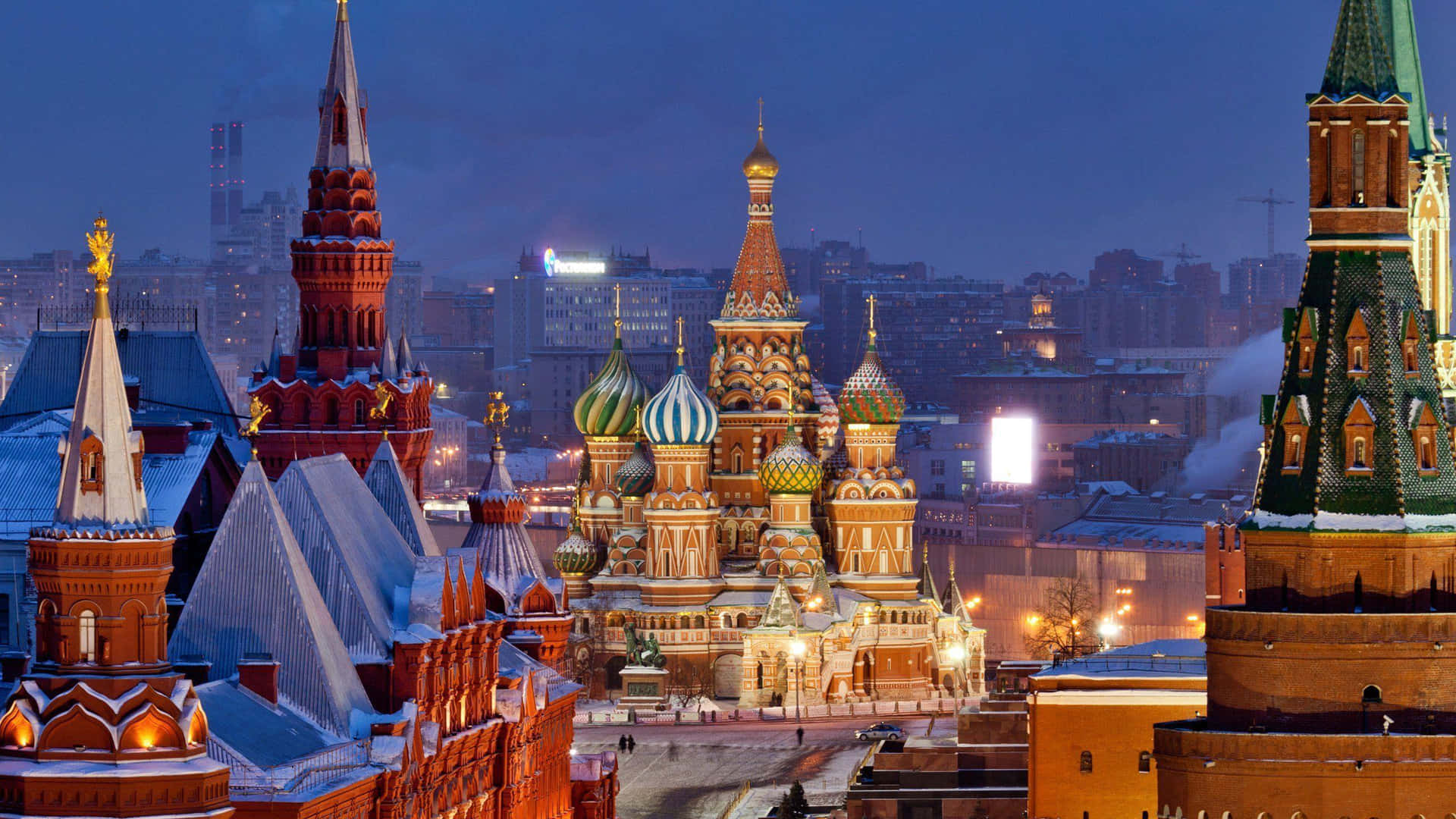 Winter Cityscape with Snow-covered Buildings and Street Lights Wallpaper