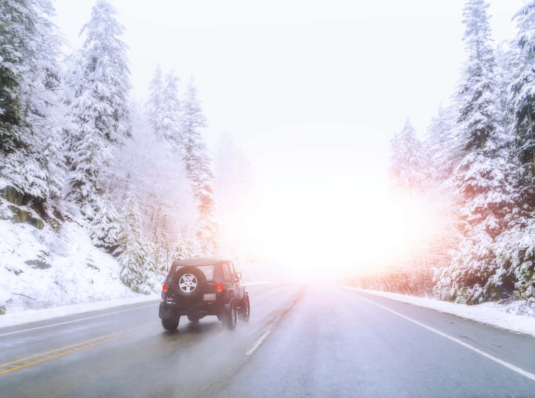 A driver navigates snowy winter roads in a picturesque landscape Wallpaper