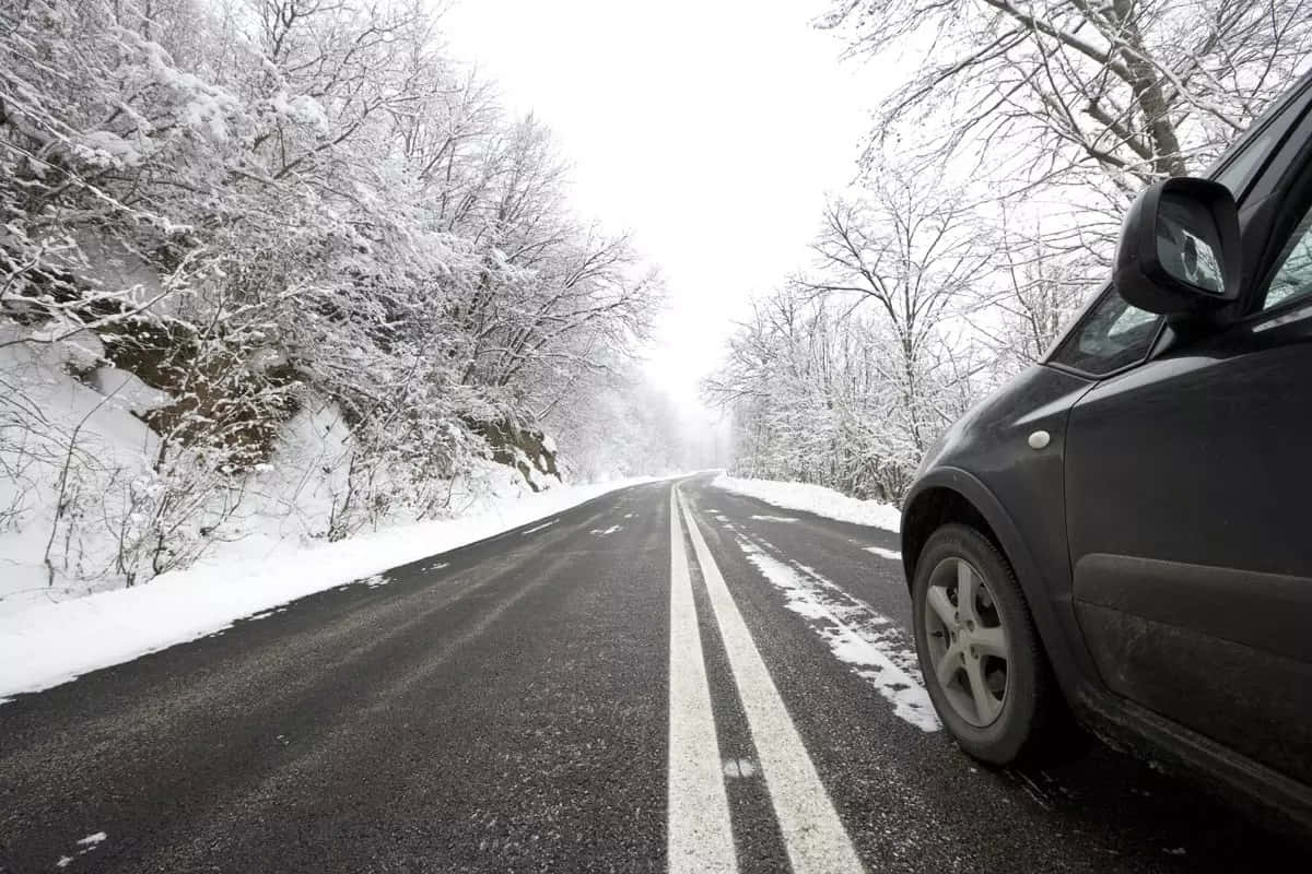 A car driving through a snowy winter road Wallpaper